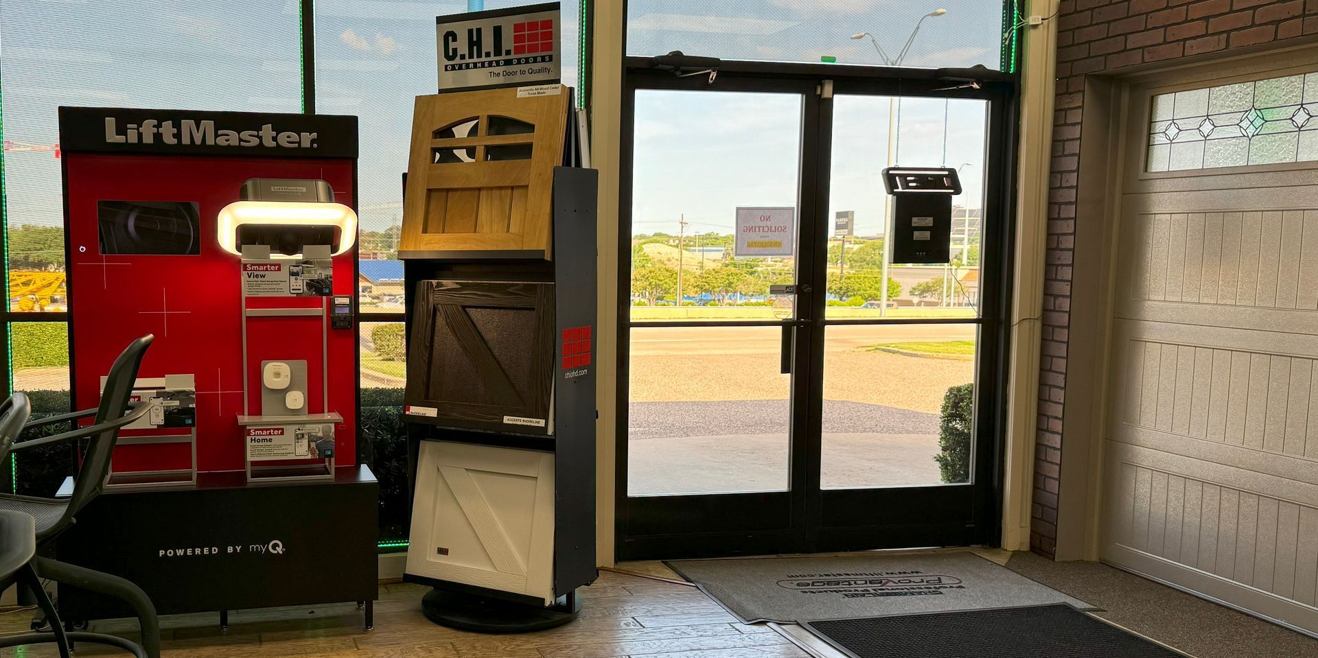 Interior shot of a storefront with a LiftMaster display and door samples, leading to an open doorway.