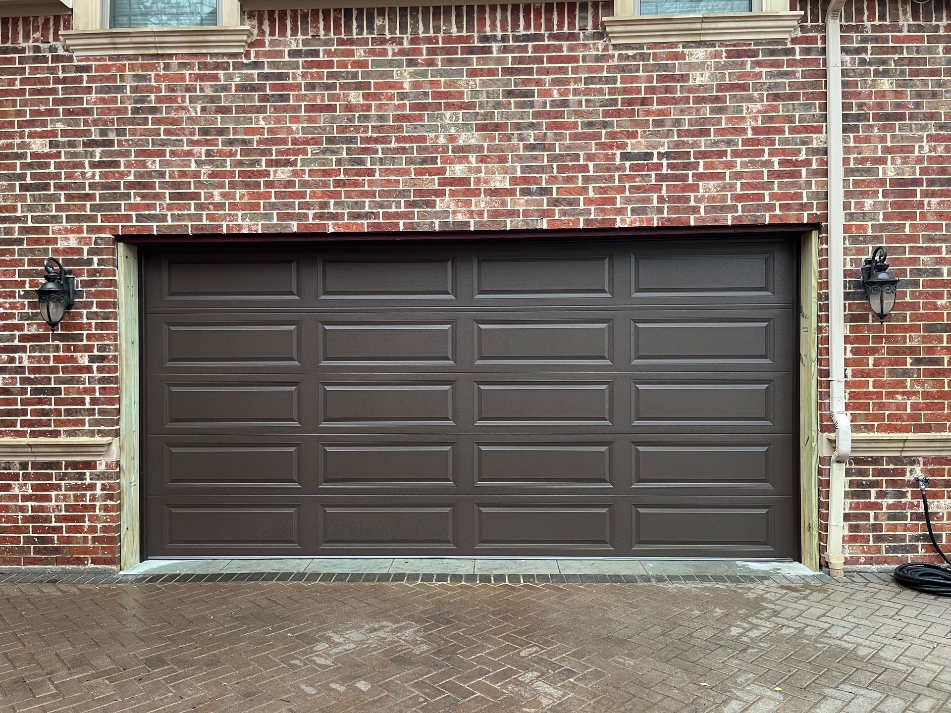 Brown garage door on a brick building exterior.