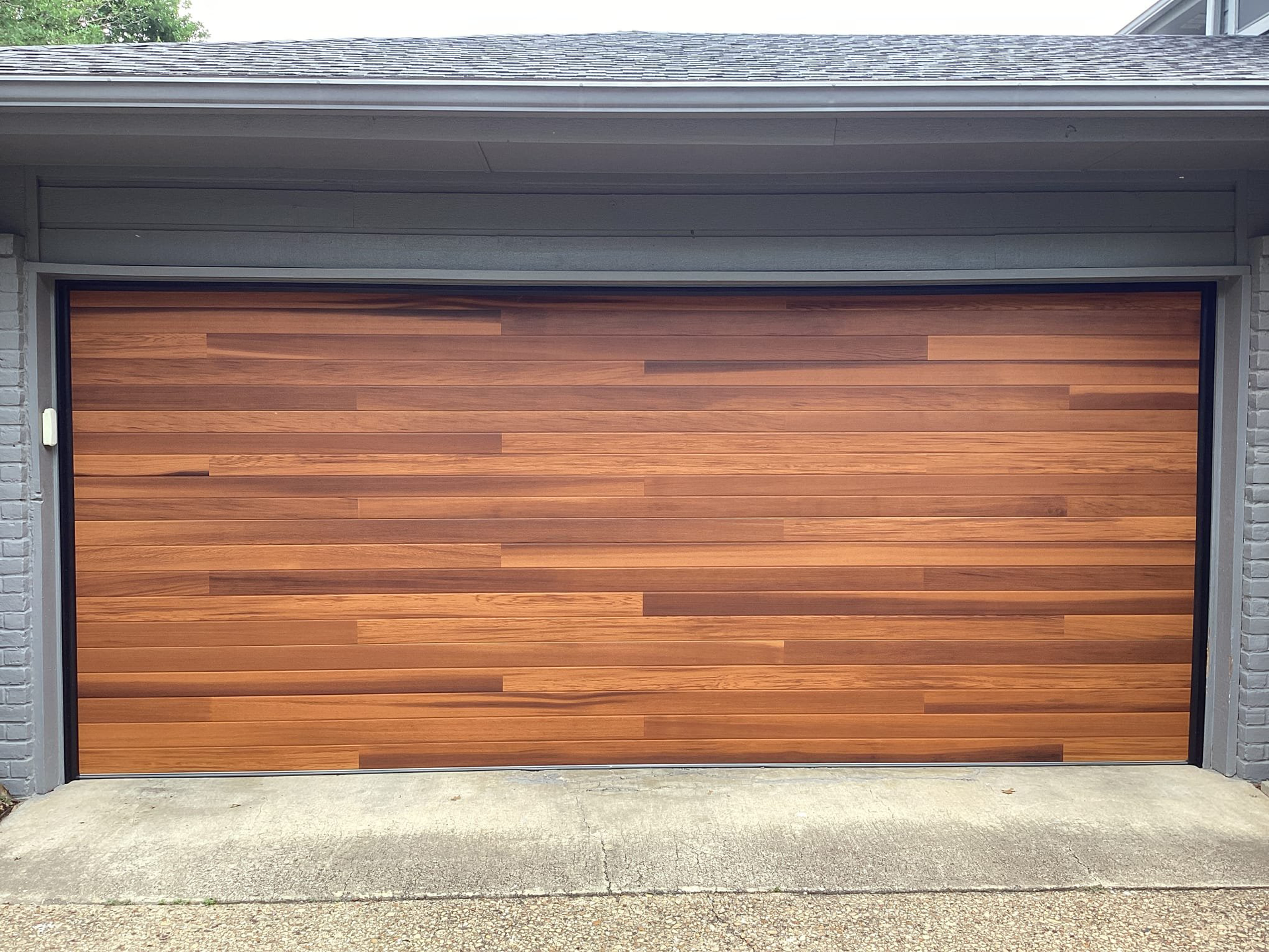 Wooden garage door, horizontal planks, brown tones, gray trim.