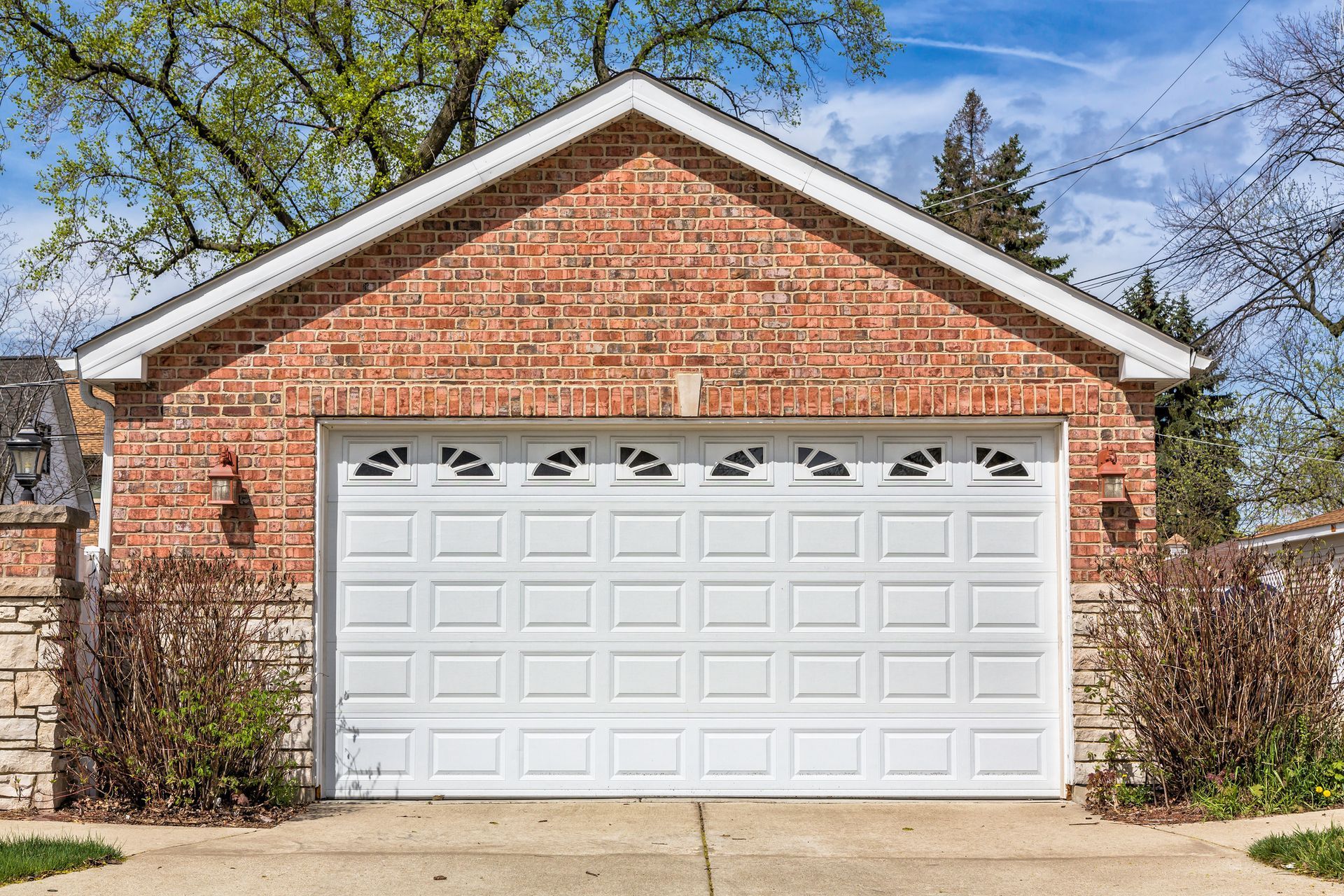 Brick garage with white garage door and concrete driveway.