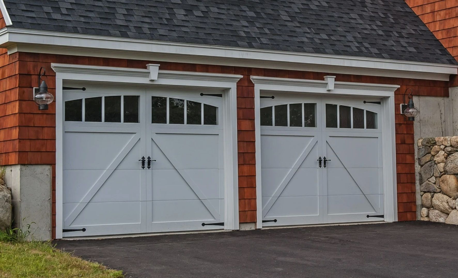 Two white carriage-style garage doors with windows on a red shingled building exterior.