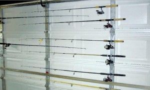 Fishing rods hanging on a garage door, organized horizontally in a rack.