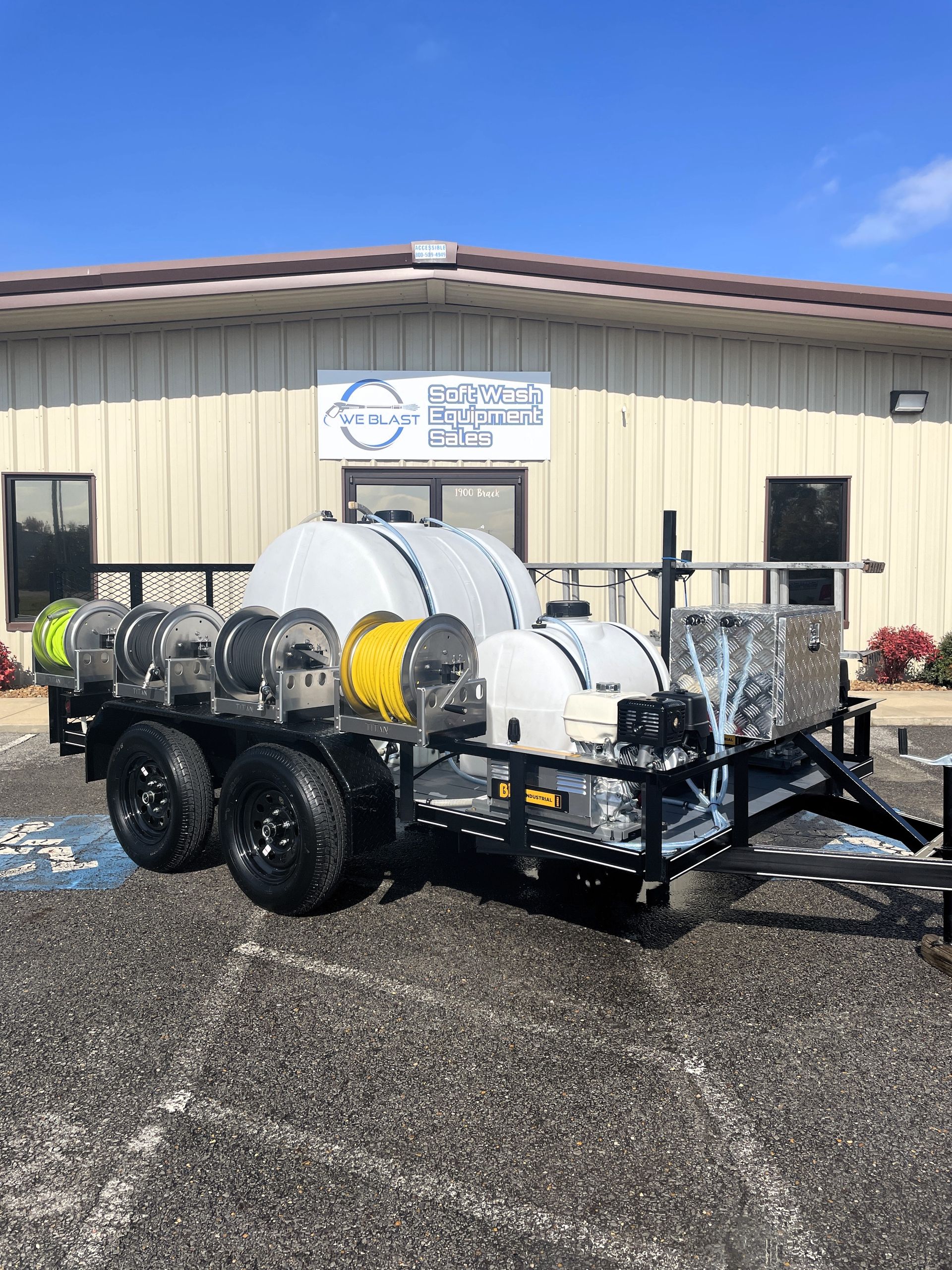 A trailer with a hose attached to it is parked in front of a building.