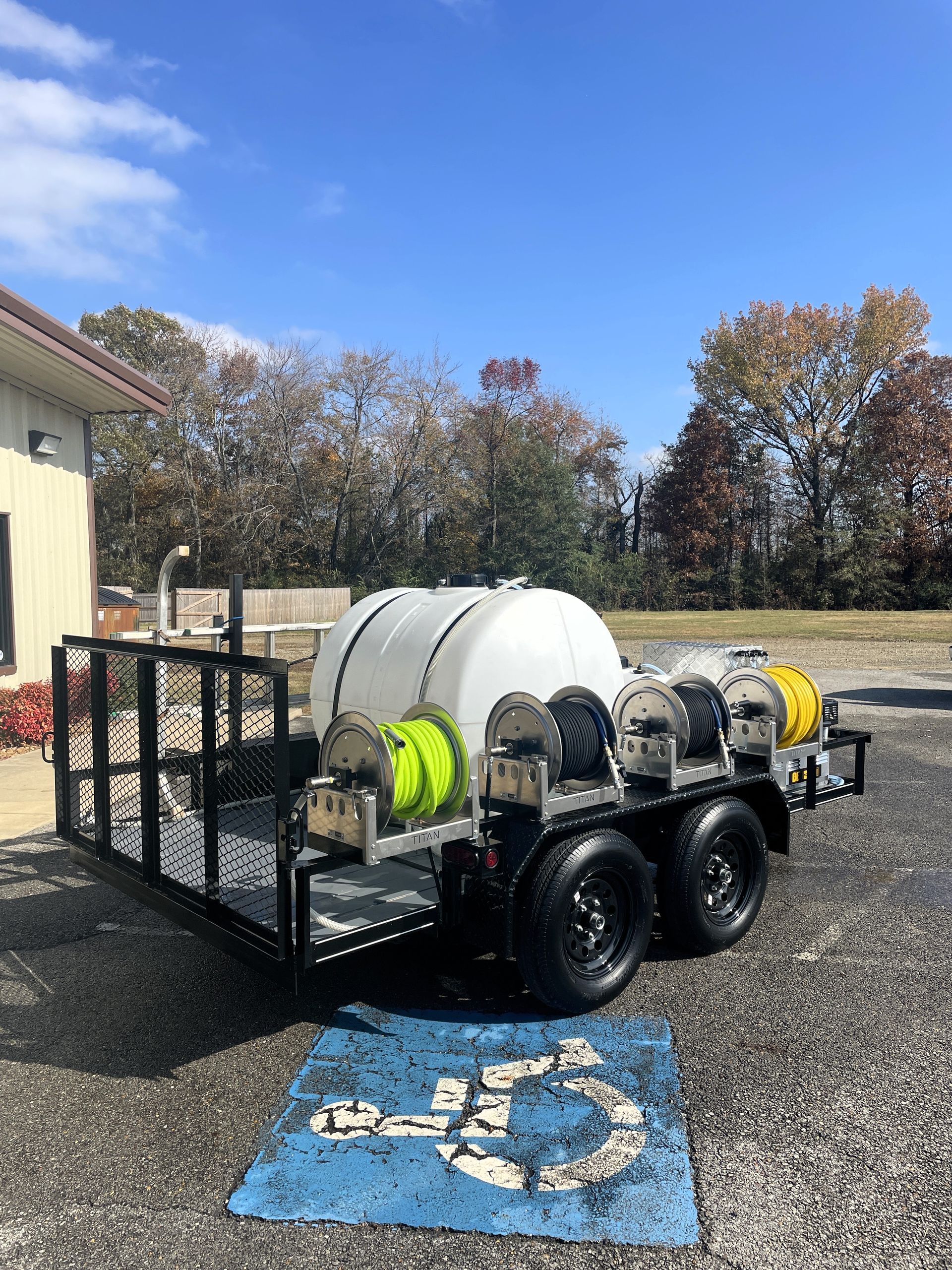 A trailer with a hose attached to it is parked in a handicapped parking spot.