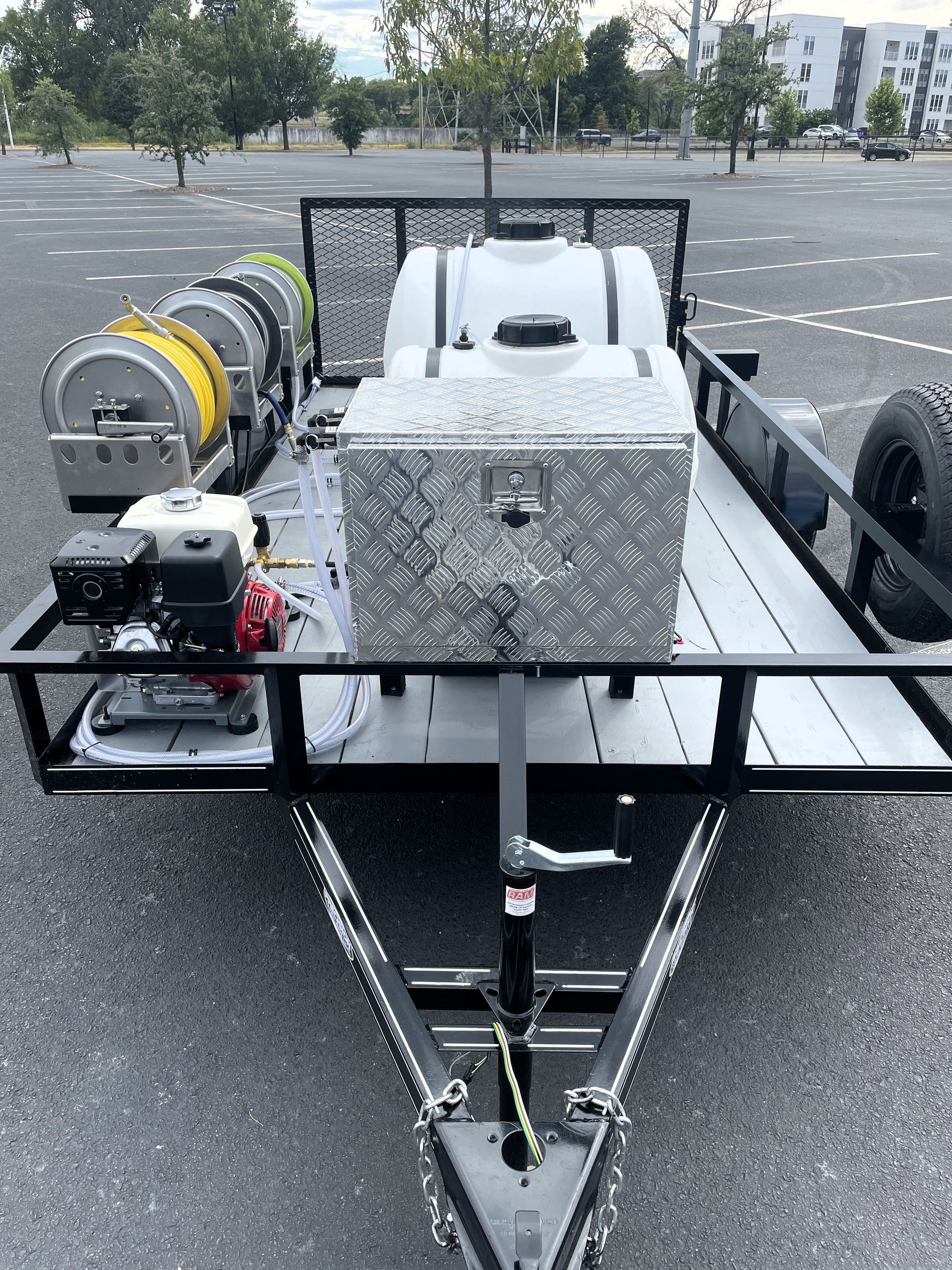 A trailer with a hose attached to it is parked in a parking lot.