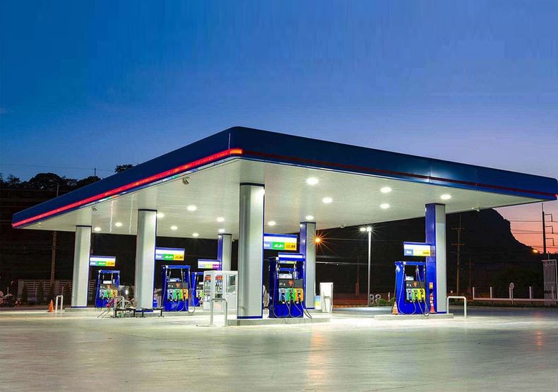 Empty gas station at dusk with bright blue pumps and white canopy