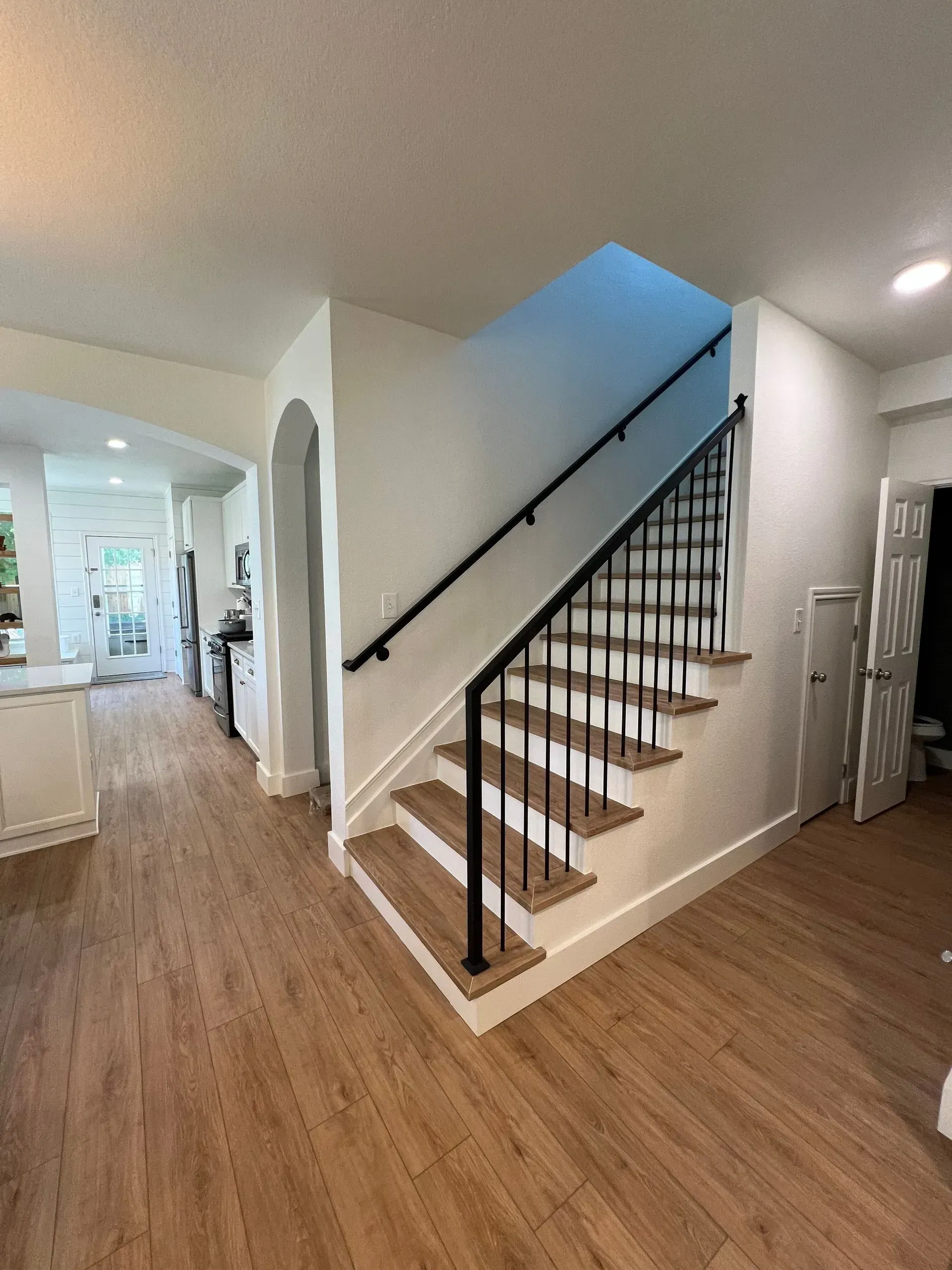 A staircase in a house with wooden steps and a black railing.