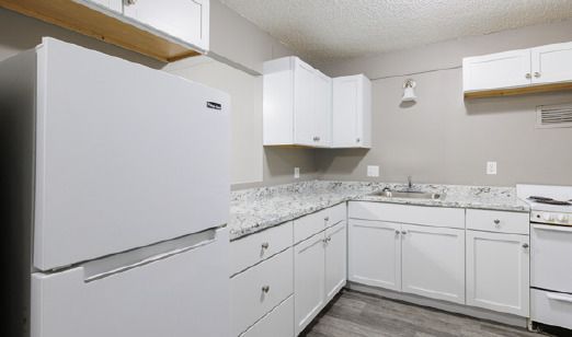 A kitchen with white cabinets and a white refrigerator.