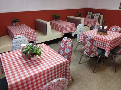 A restaurant dining area featuring several tables covered with red-and-white checkered tablecloths and patterned chairs.