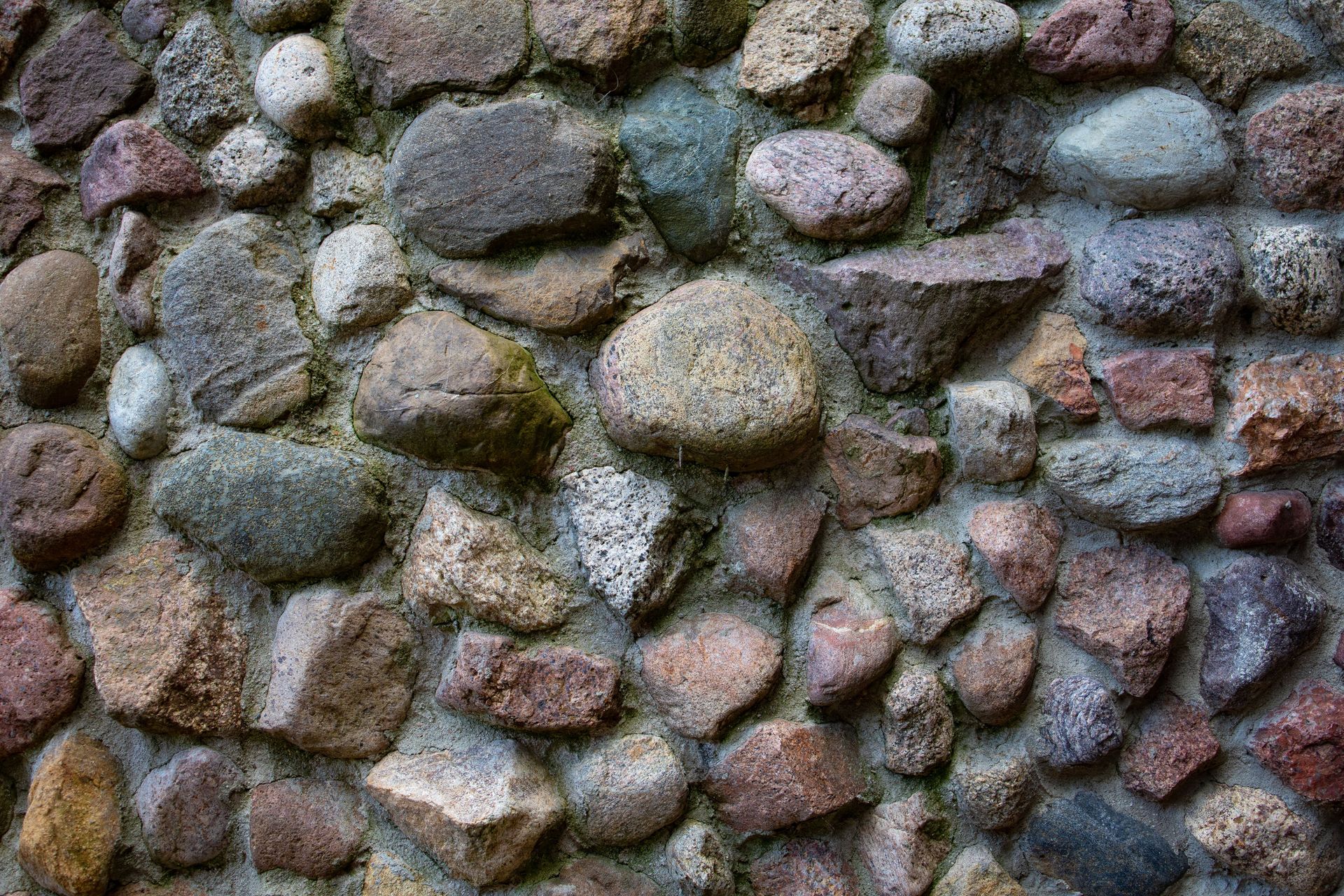 Close-up of a rough stone wall made of irregular gray and brown rocks