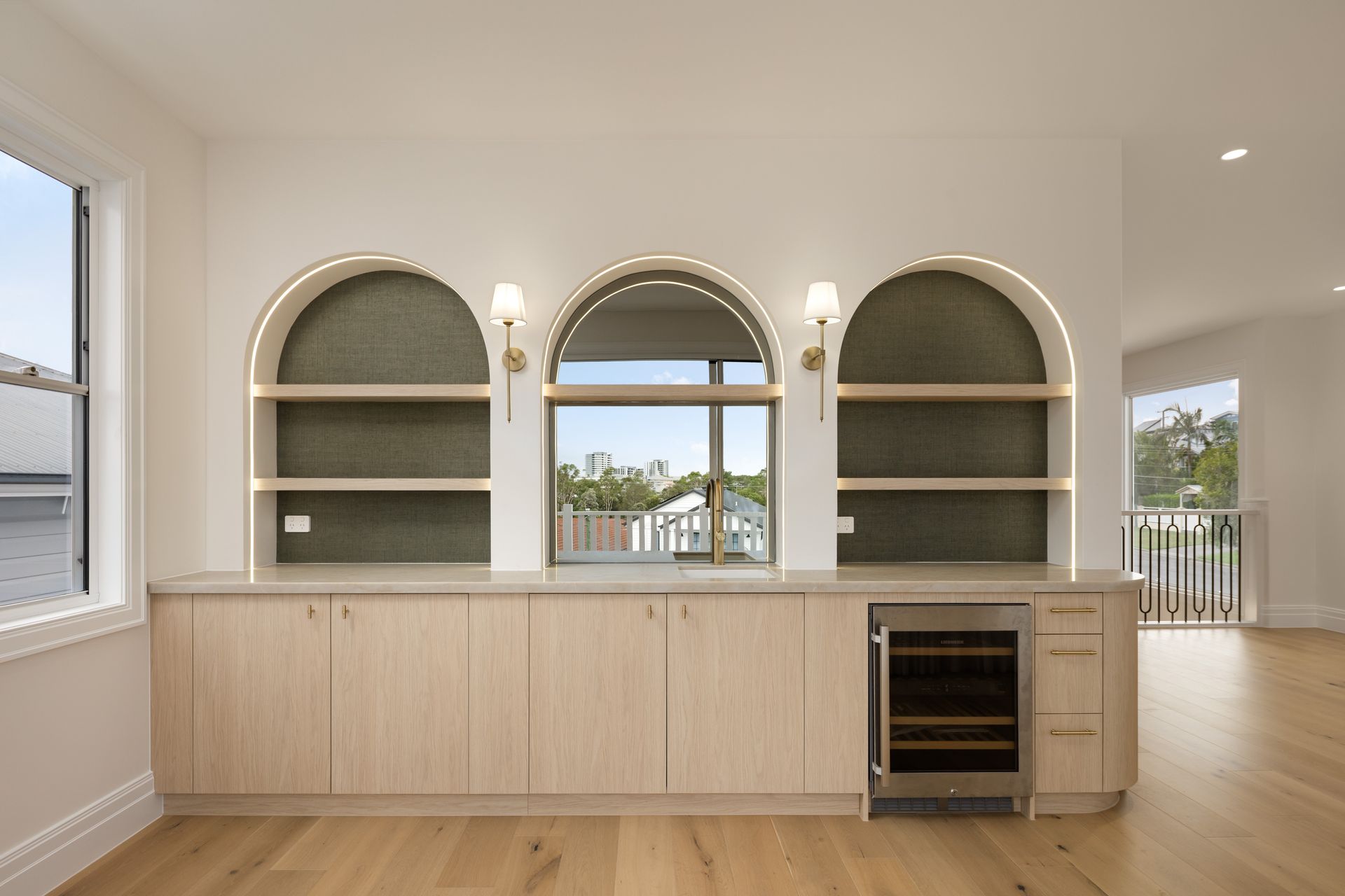 Built-in alcove with wood cabinetry, stone countertop, and three backlit shelves.
