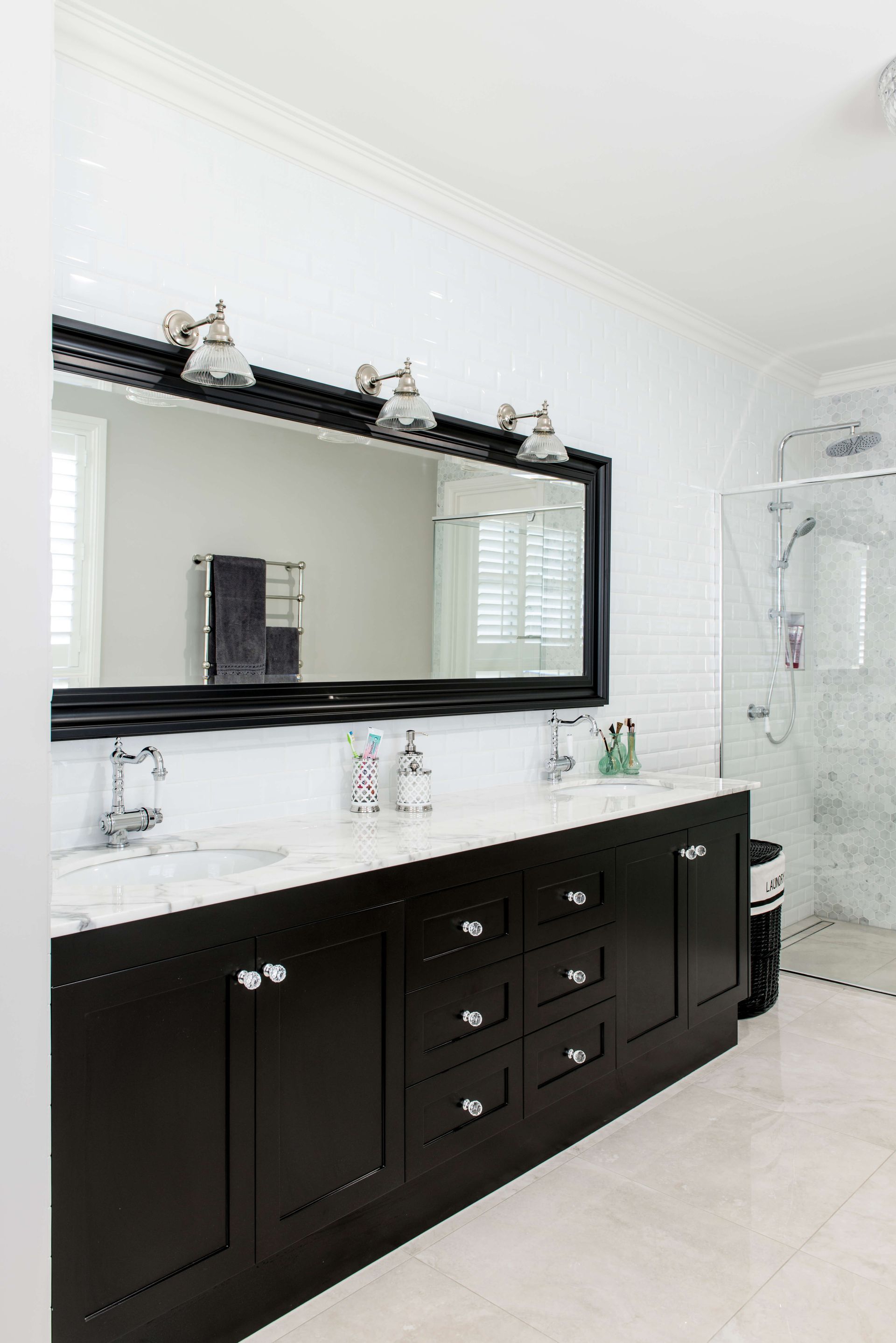 Bright white bathroom with dark vanity, large mirror, and glass shower enclosure