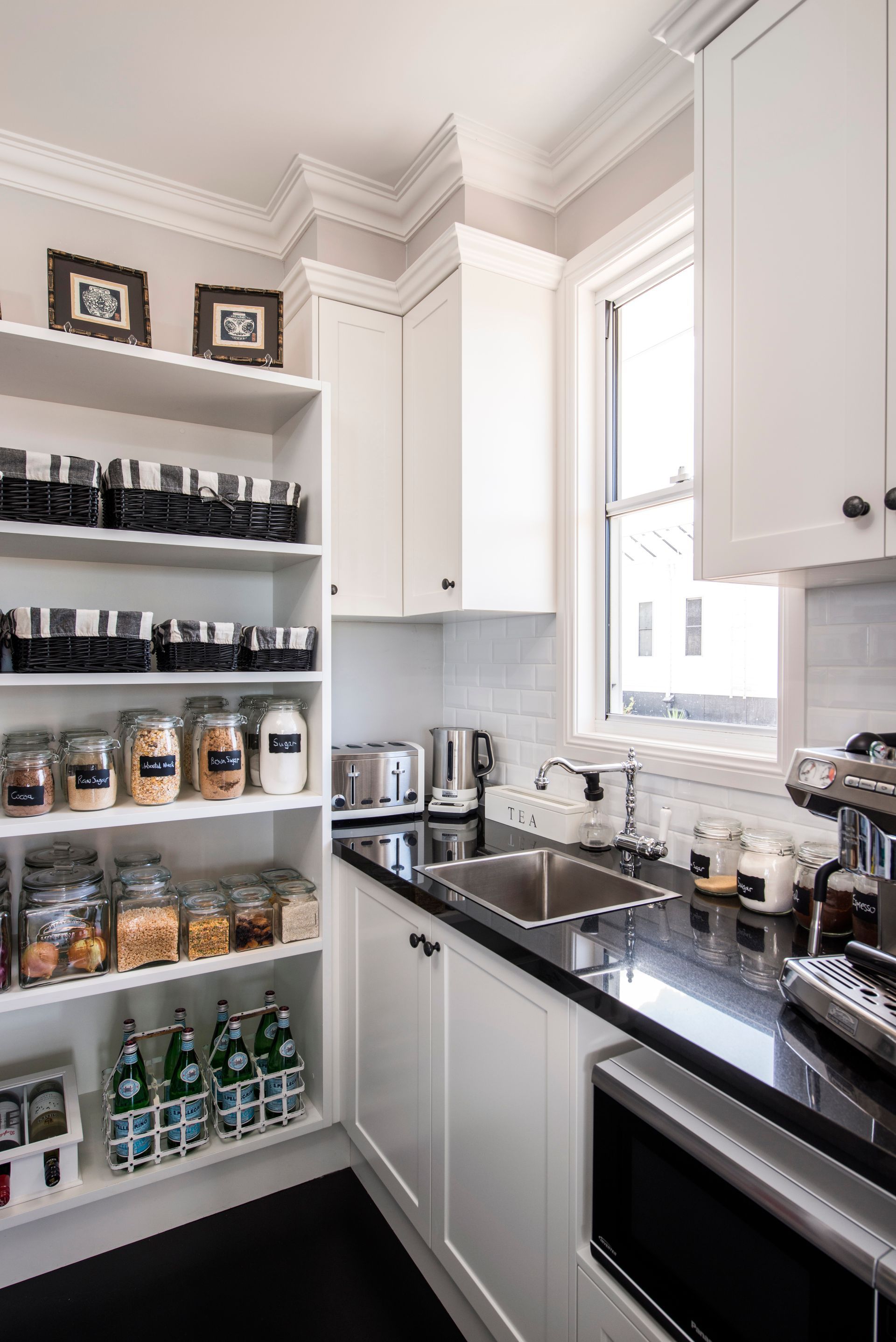 Modern kitchen with a large island, bar stools, dark cabinets, and wood floors in a bright room Modern kitchen with a large island, bar stools, dark cabinets, and wood floors in a bright room