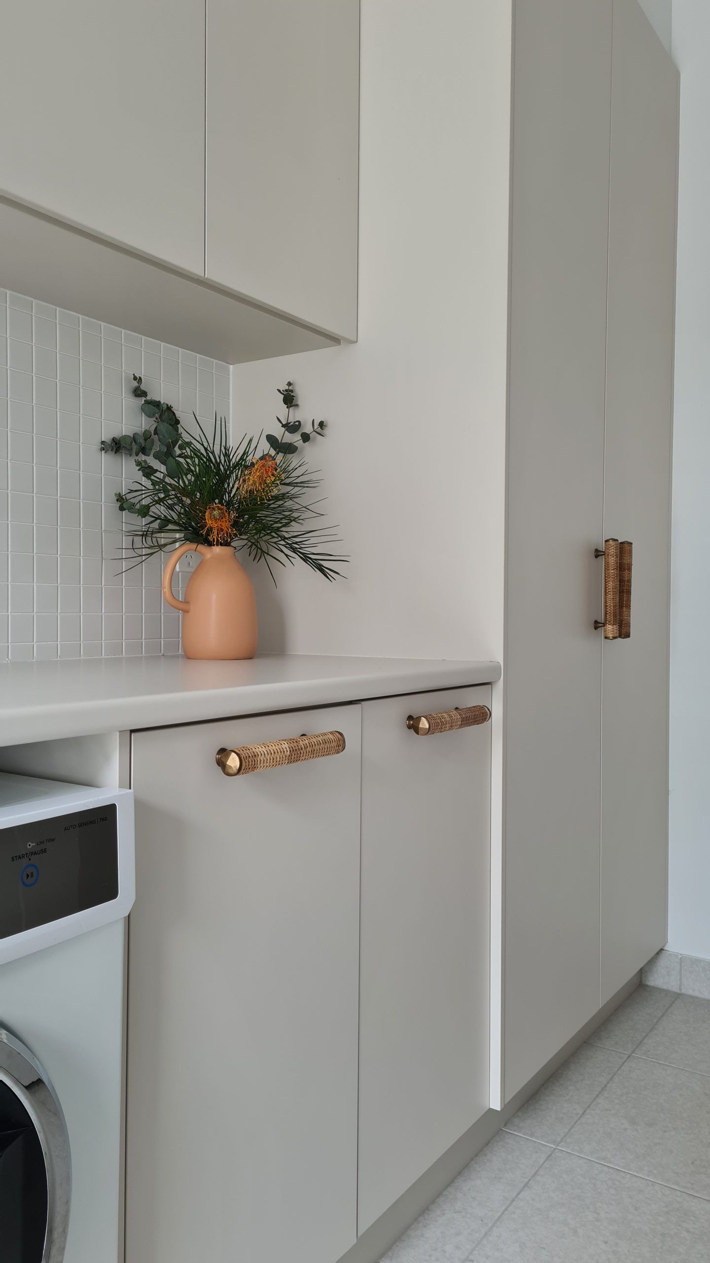 Modern kitchen nook with white cabinets, a peach vase of flowers, and a built-in oven.