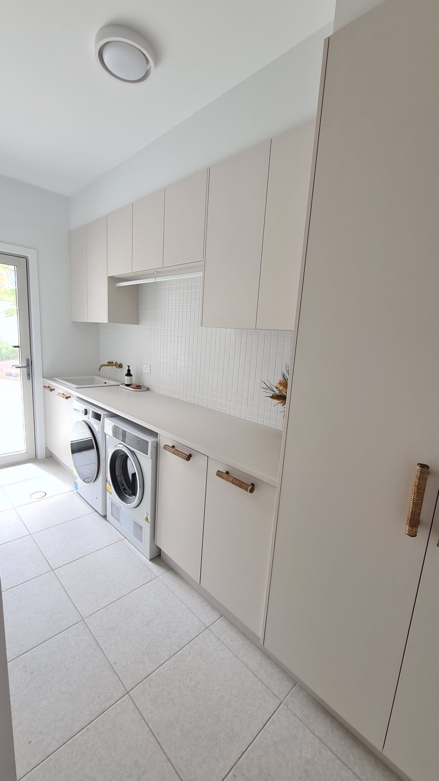 Small laundry room with stacked washer and dryer, white cabinets, and tiled floor