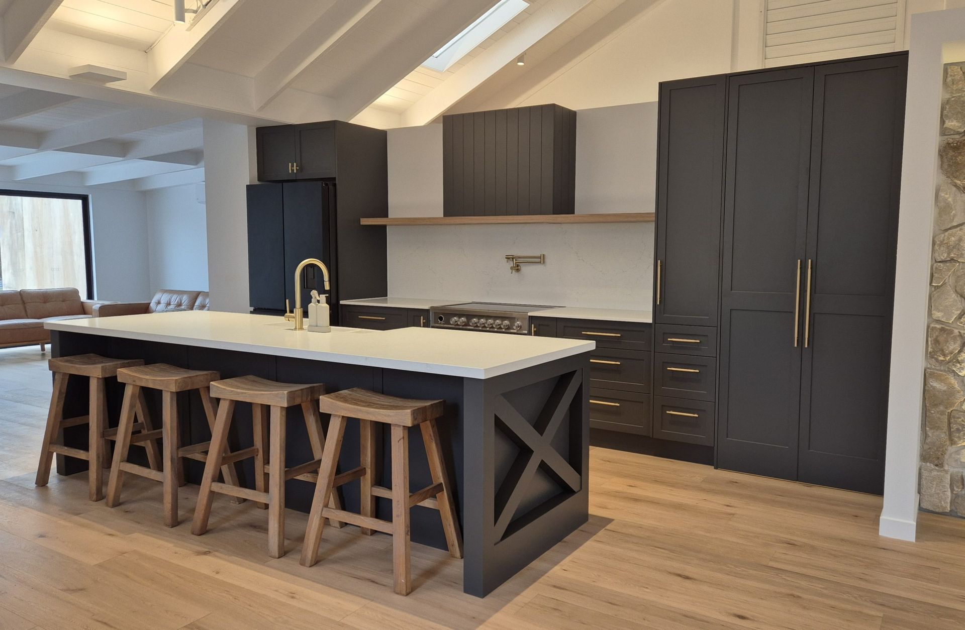 Modern kitchen with a large island, bar stools, dark cabinets, and wood floors in a bright room Modern kitchen with a large island, bar stools, dark cabinets, and wood floors in a bright room
