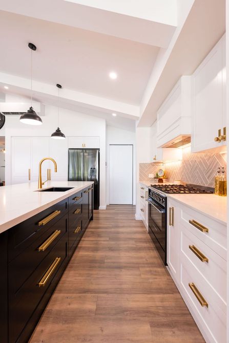 Modern minimalist kitchen with dark cabinets, white island, and large windows overlooking a green backyard Modern minimalist kitchen with dark cabinets, white island, and large windows overlooking a green backyard