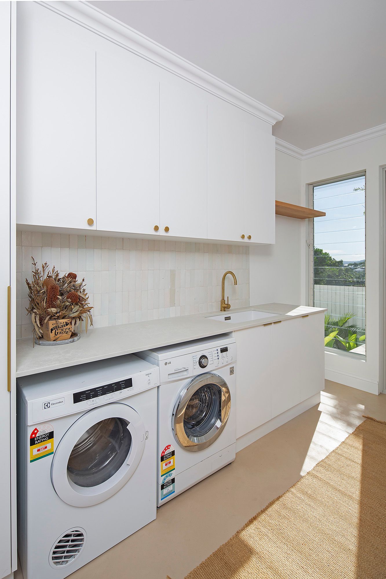 Laundry room with white cabinets, washer and dryer, and a small counter by a window.