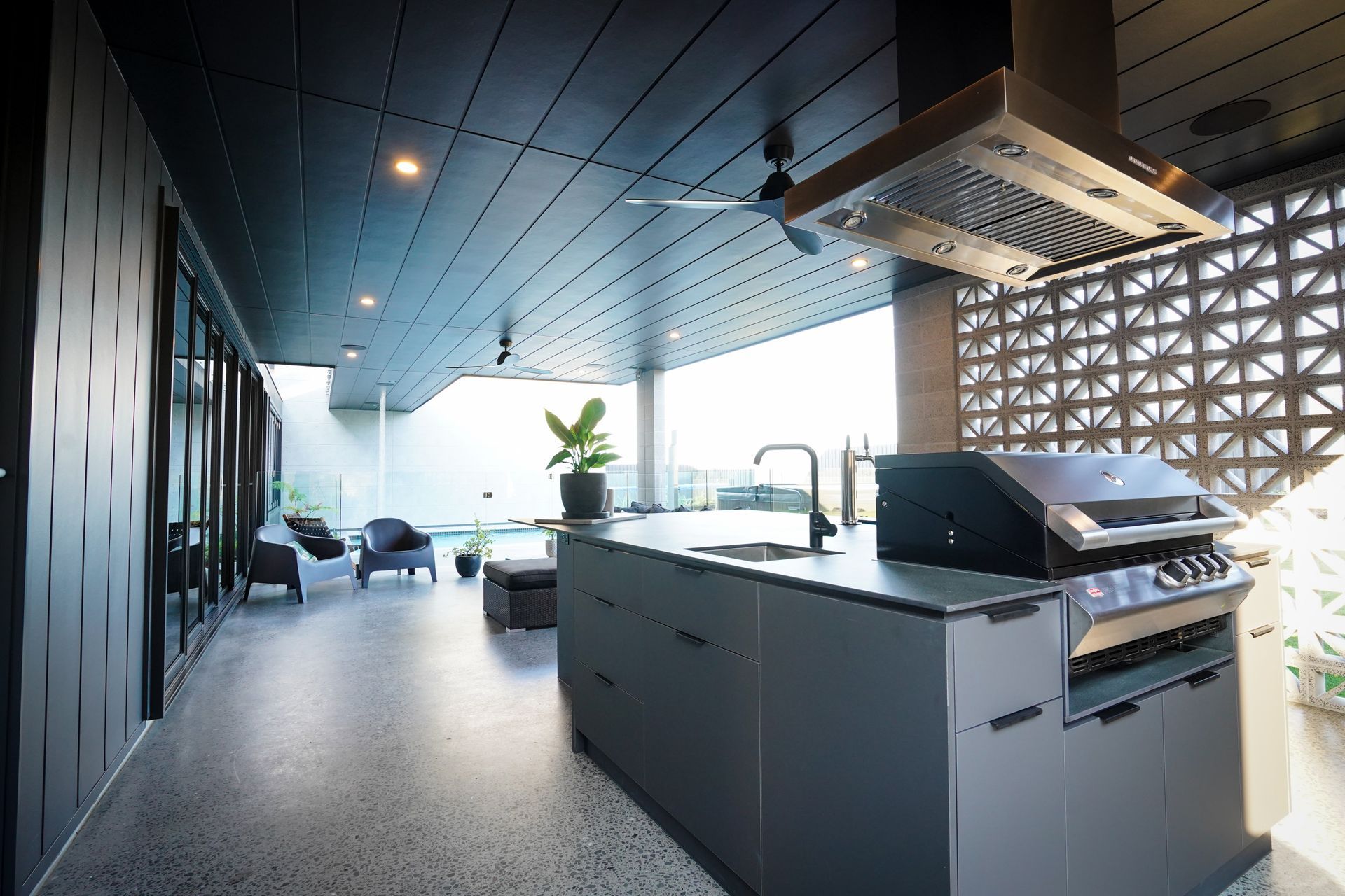 Modern restaurant interior with a central communal table, black stools, and shelves of plants and decor
