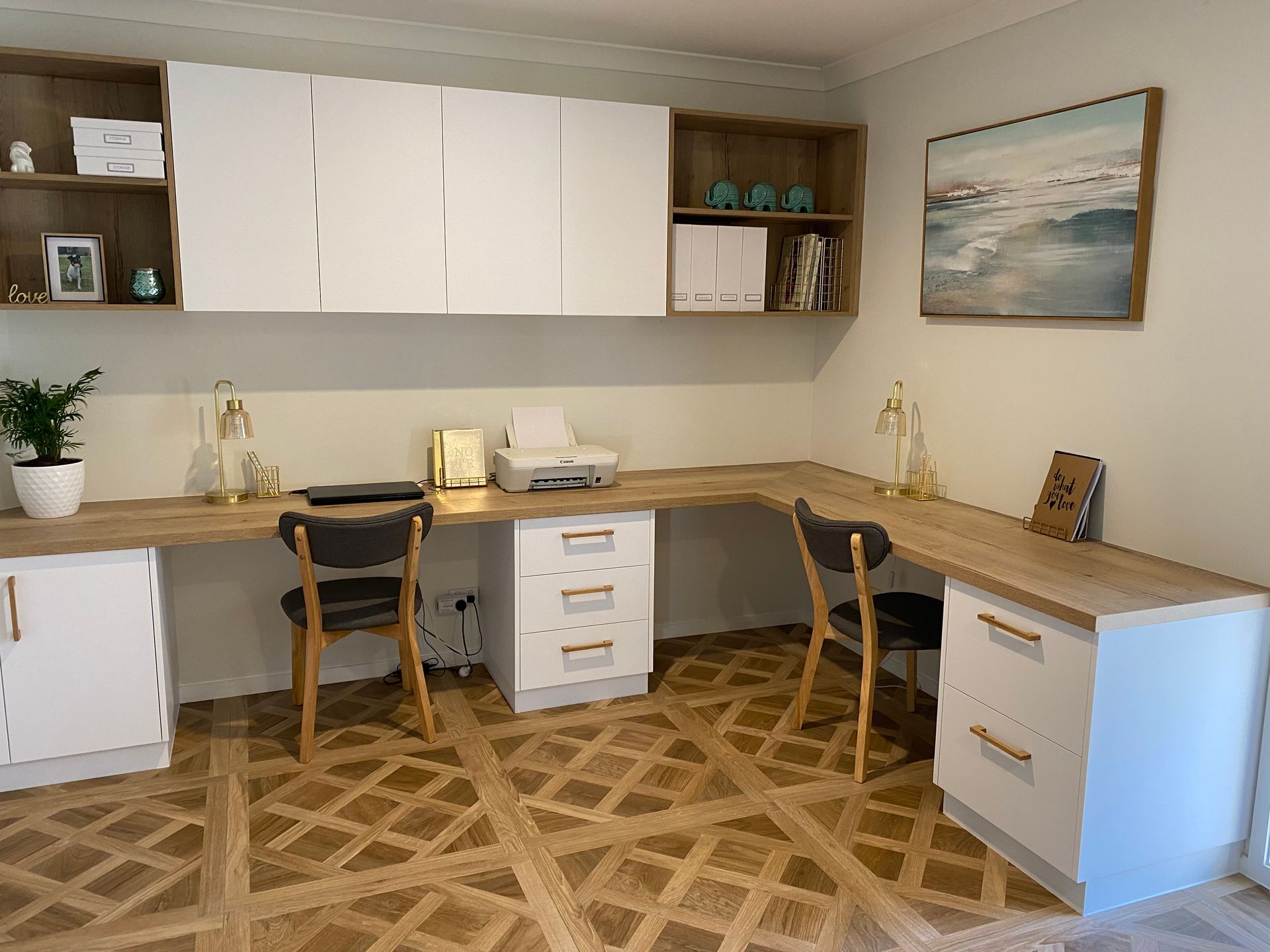 L-shaped home office with white cabinets, wood desk, two chairs, and patterned tile floor.