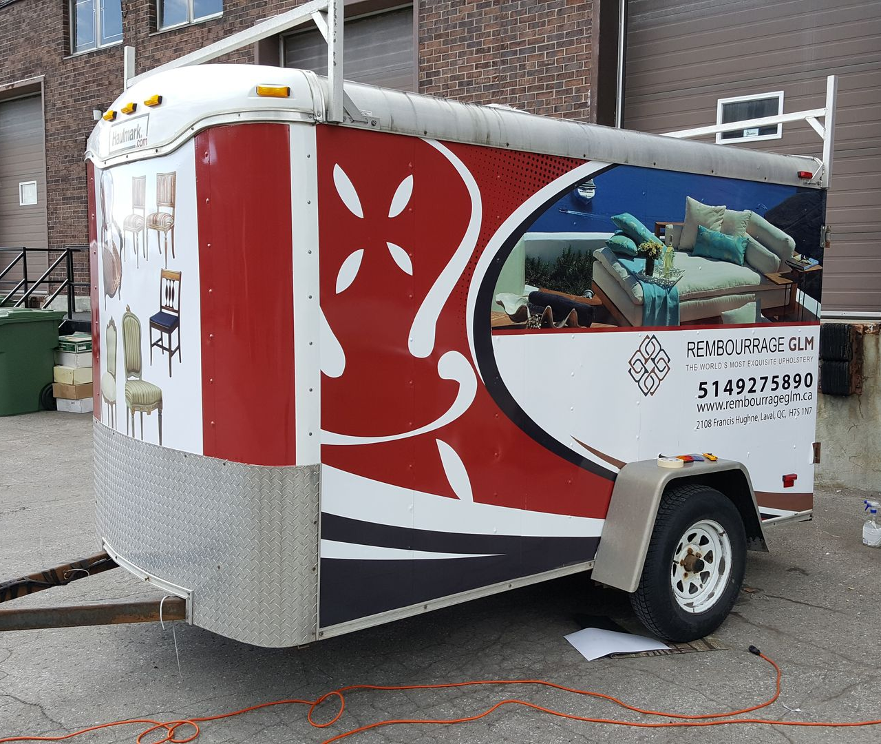 A trailer with furniture advertisement, red and white colors, parked outdoors.
