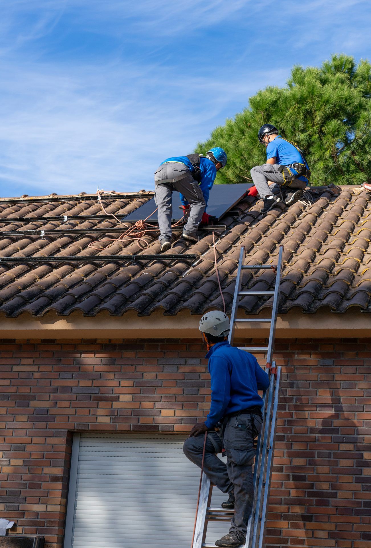 Roofer climbing a ladder onto a tiled residential roof