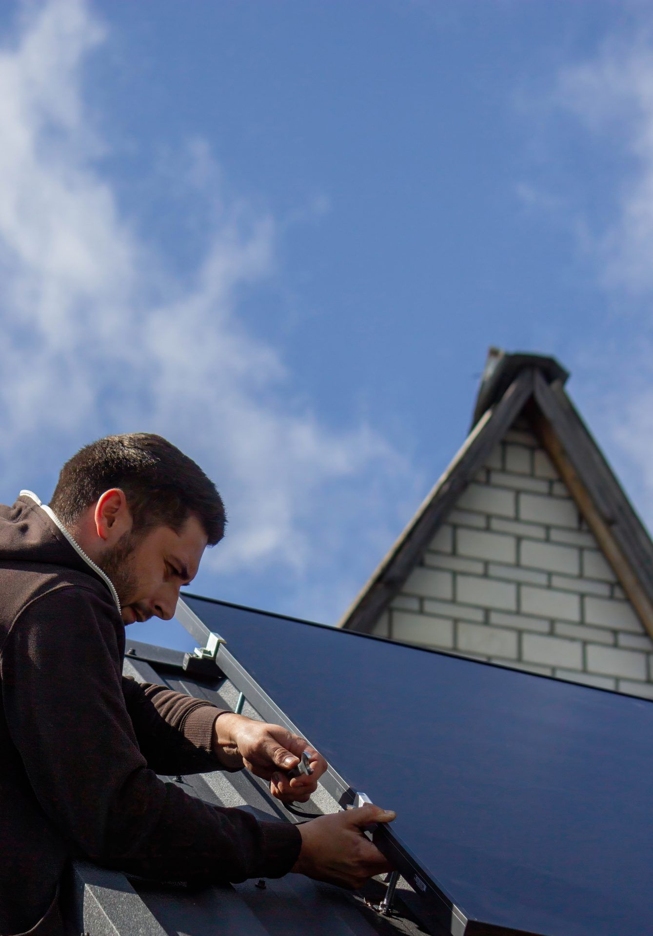 Roofer kneeling beside a skylight while working on a residential roof