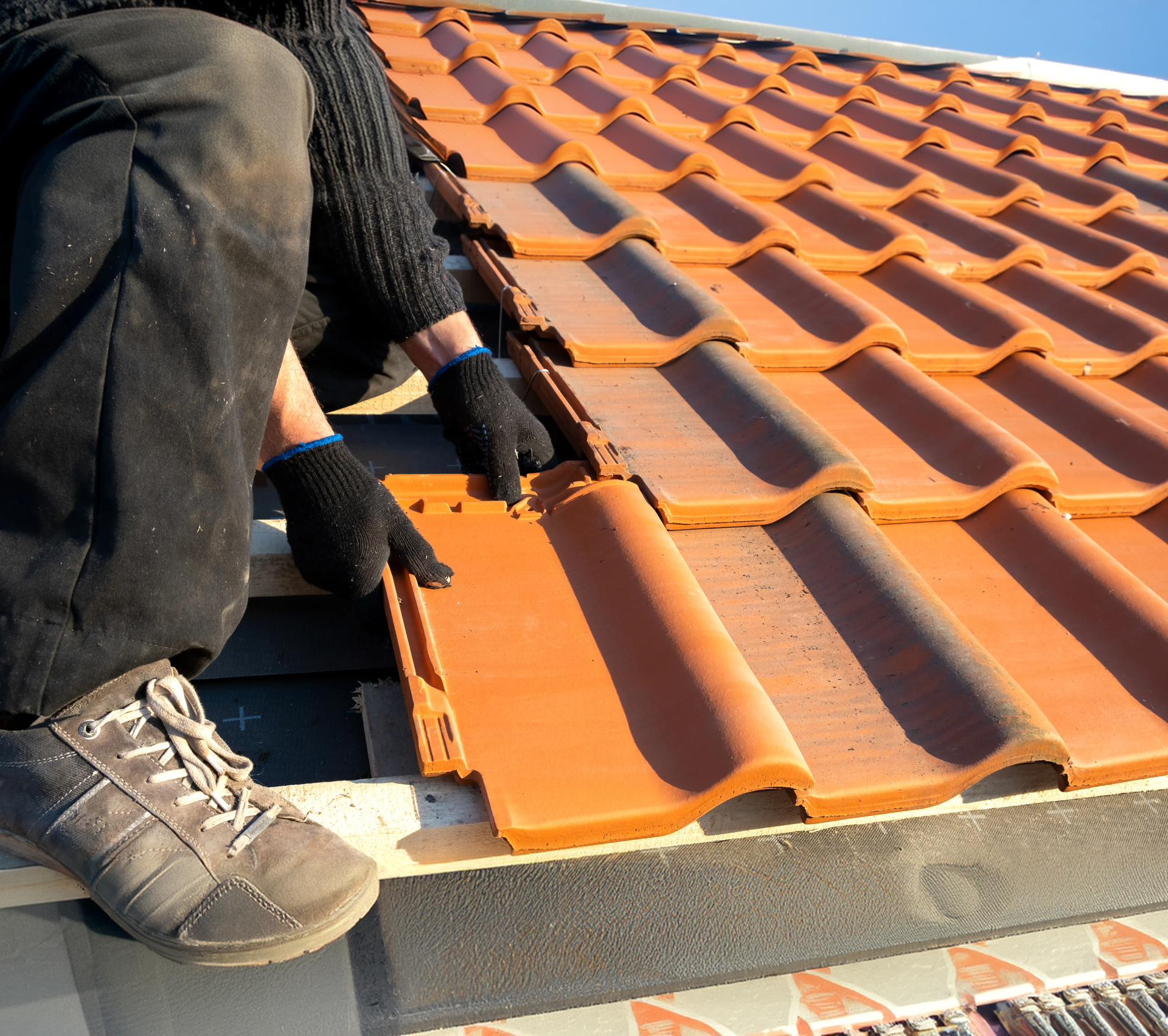Roofer installing terracotta tile roofing