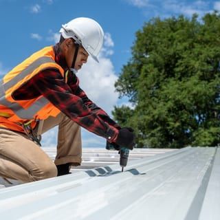 Roof Replacement in Florence, OR - roofer fastening metal roofing panels
