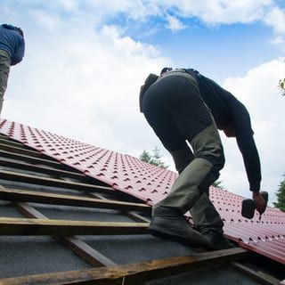 Roof Replacement in Waldport, OR - roofers installing red metal roofing