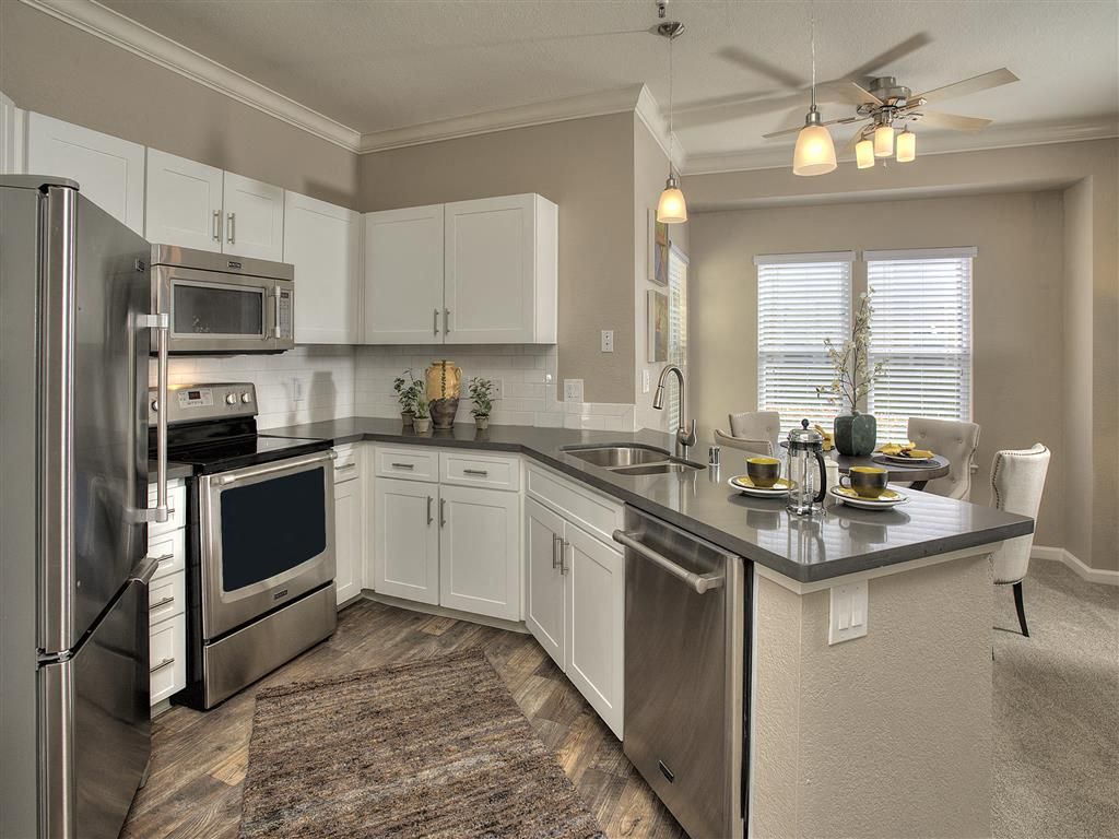 Modern kitchen with stainless steel appliances, white cabinets, gray countertops, and an island at Iron Point at Prairie Oaks apartments in Folsom, CA.