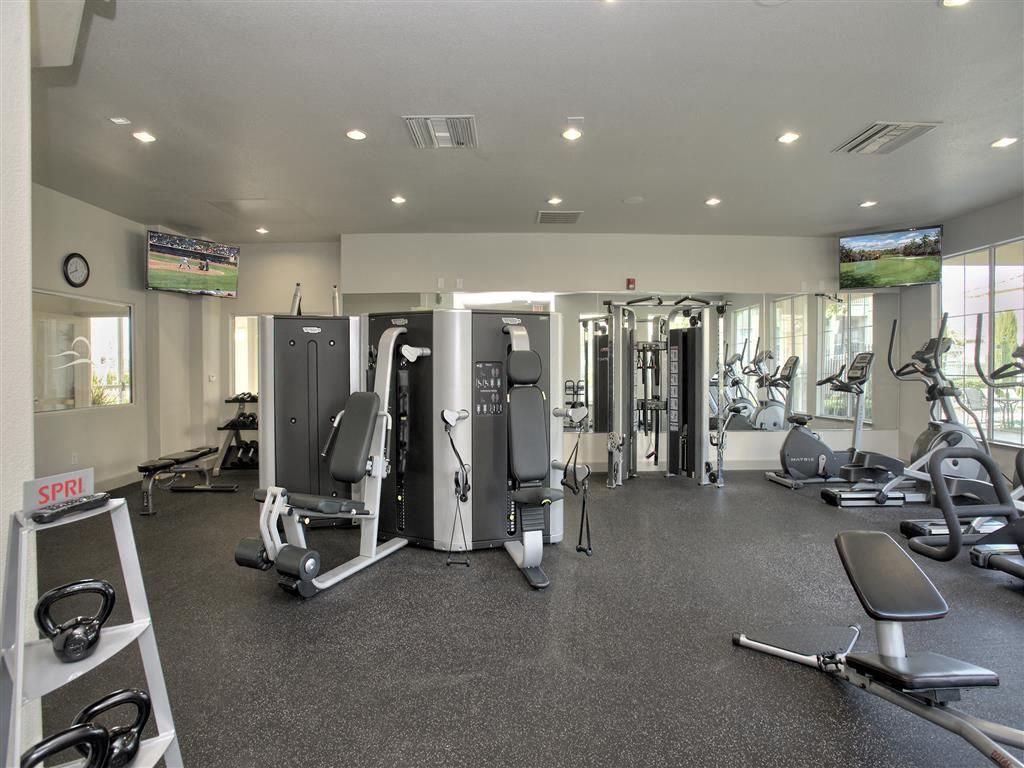 Indoor community gym with cardio equipment and weight machines at Iron Point at Prairie Oaks apartments in Folsom, CA.