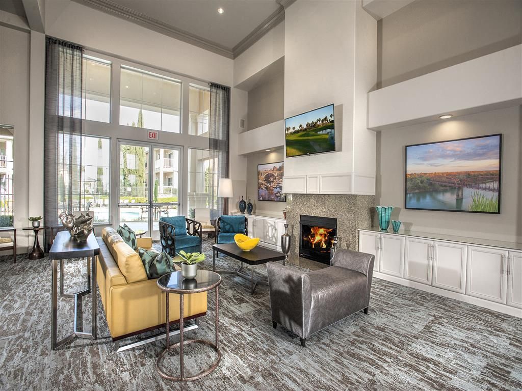 Modern community lounge with a fireplace, large windows, and comfortable seating at Iron Point at Prairie Oaks apartments in Folsom, CA.