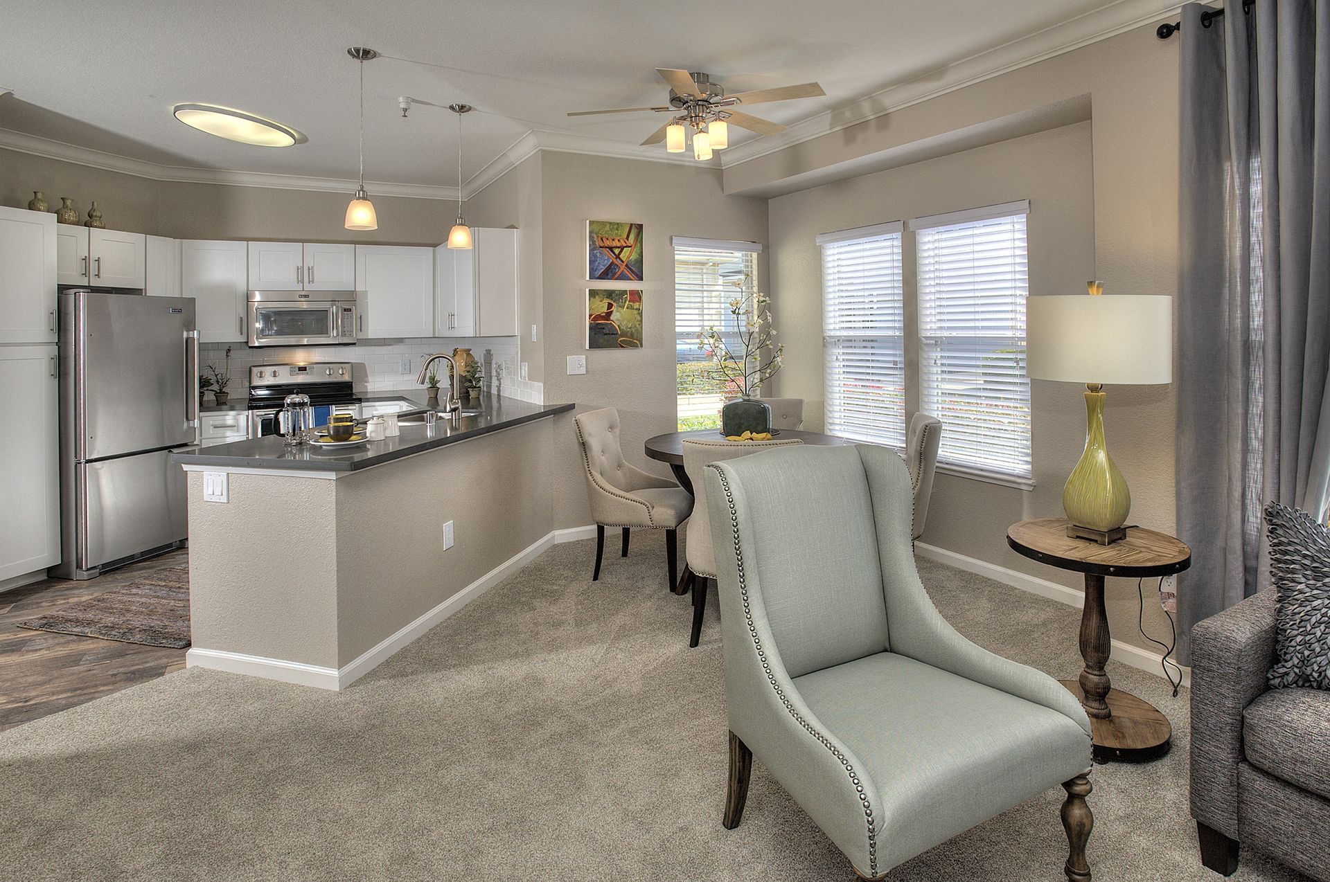 Open-concept apartment living space with kitchen island, white cabinets, and dining area at Iron Point at Prairie Oaks apartments in Folsom, CA.