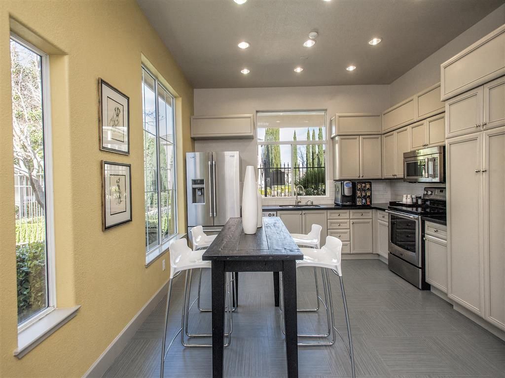 Modern kitchen in an apartment featuring white cabinets, stainless steel appliances, and a dark dining island at Iron Point at Prairie Oaks apartments in Folsom, CA.
