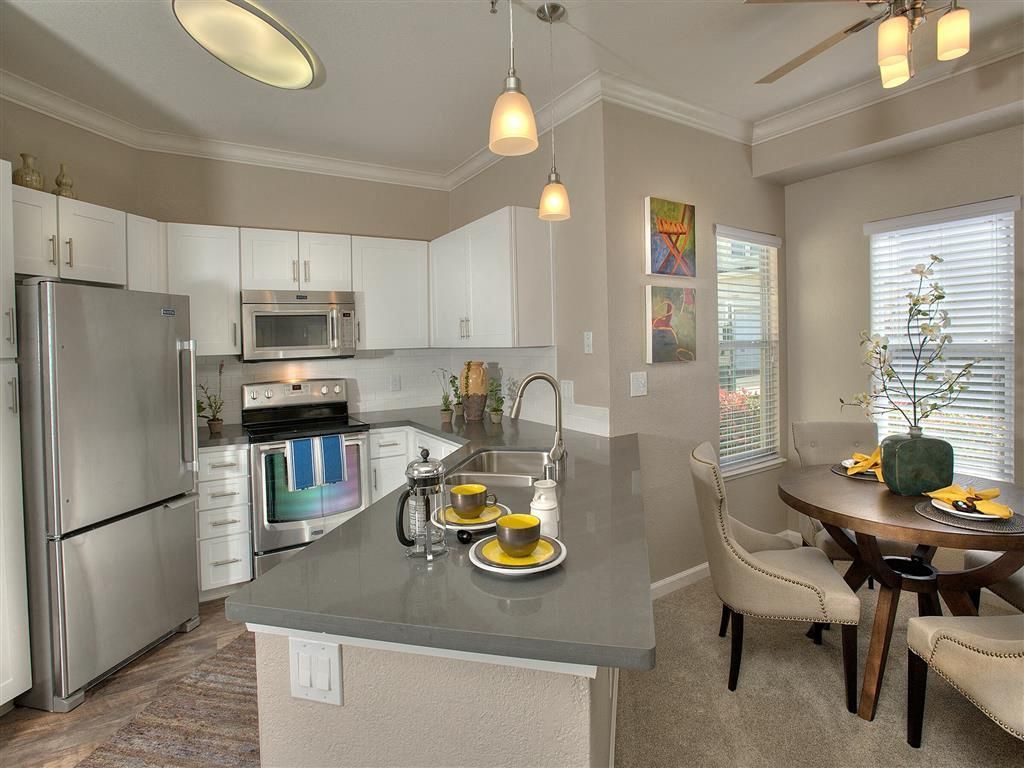 Bright modern kitchen with white cabinets, stainless steel appliances, and a gray island at Iron Point at Prairie Oaks apartments in Folsom, CA.