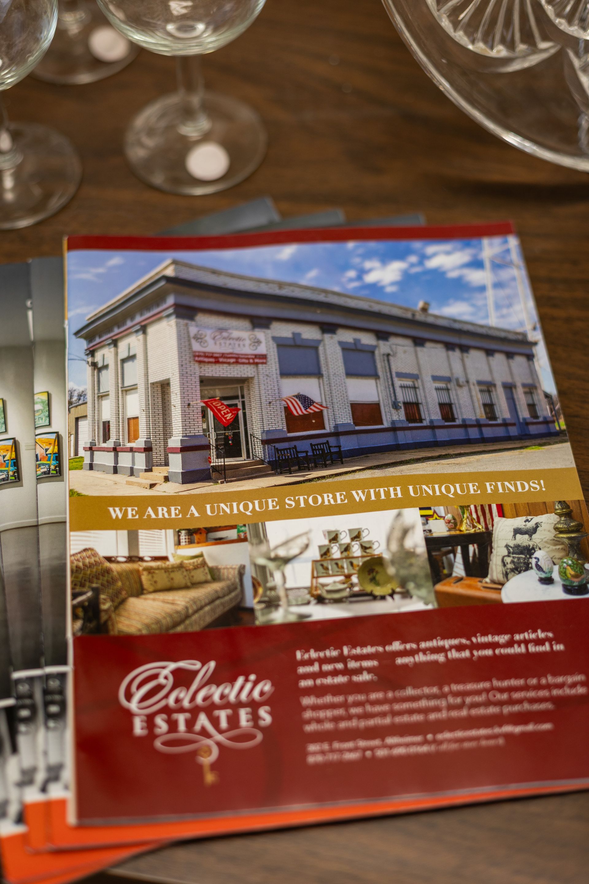 A stack of promotional brochures for Eclectic Estates showing a historic building, home decor, and business contact info.