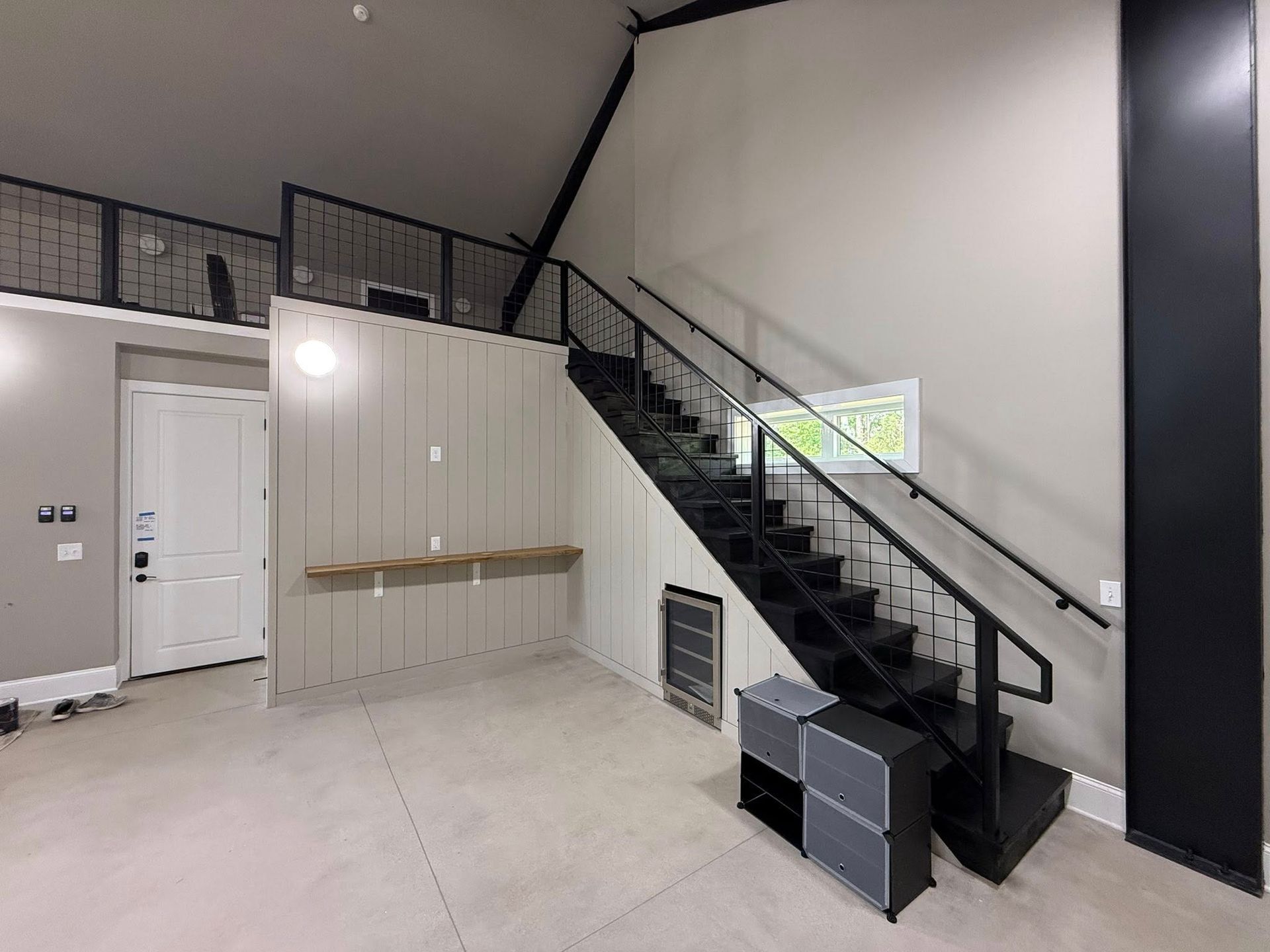 Interior with black staircase leading to loft, gray walls, and open storage.