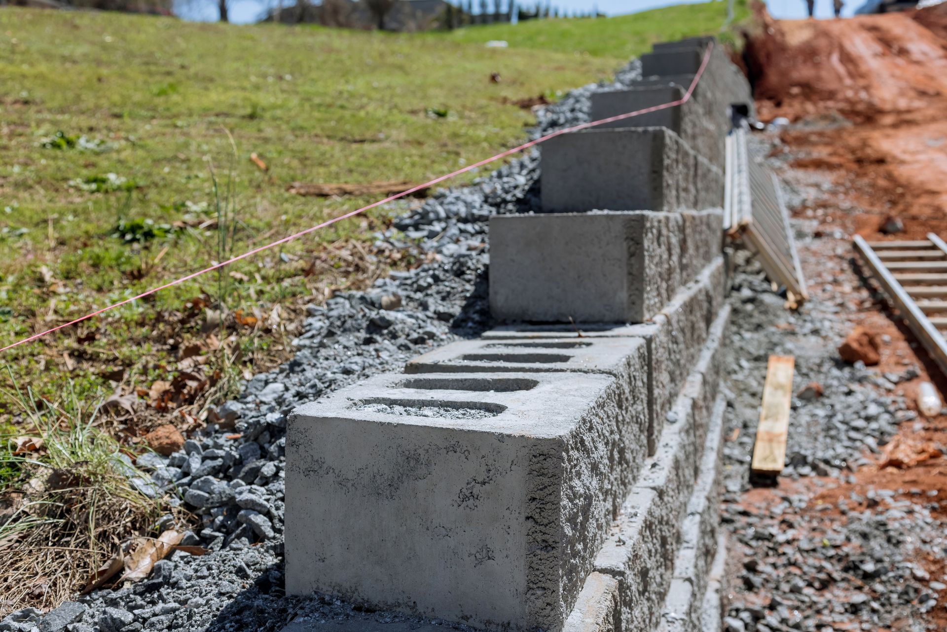 Construction of a retaining wall with concrete blocks on a hillside.