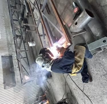 Soldador en un taller, soldando metal; chispas y luz brillante.