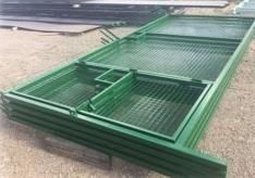 Paneles de valla de metal verde apilados al aire libre.