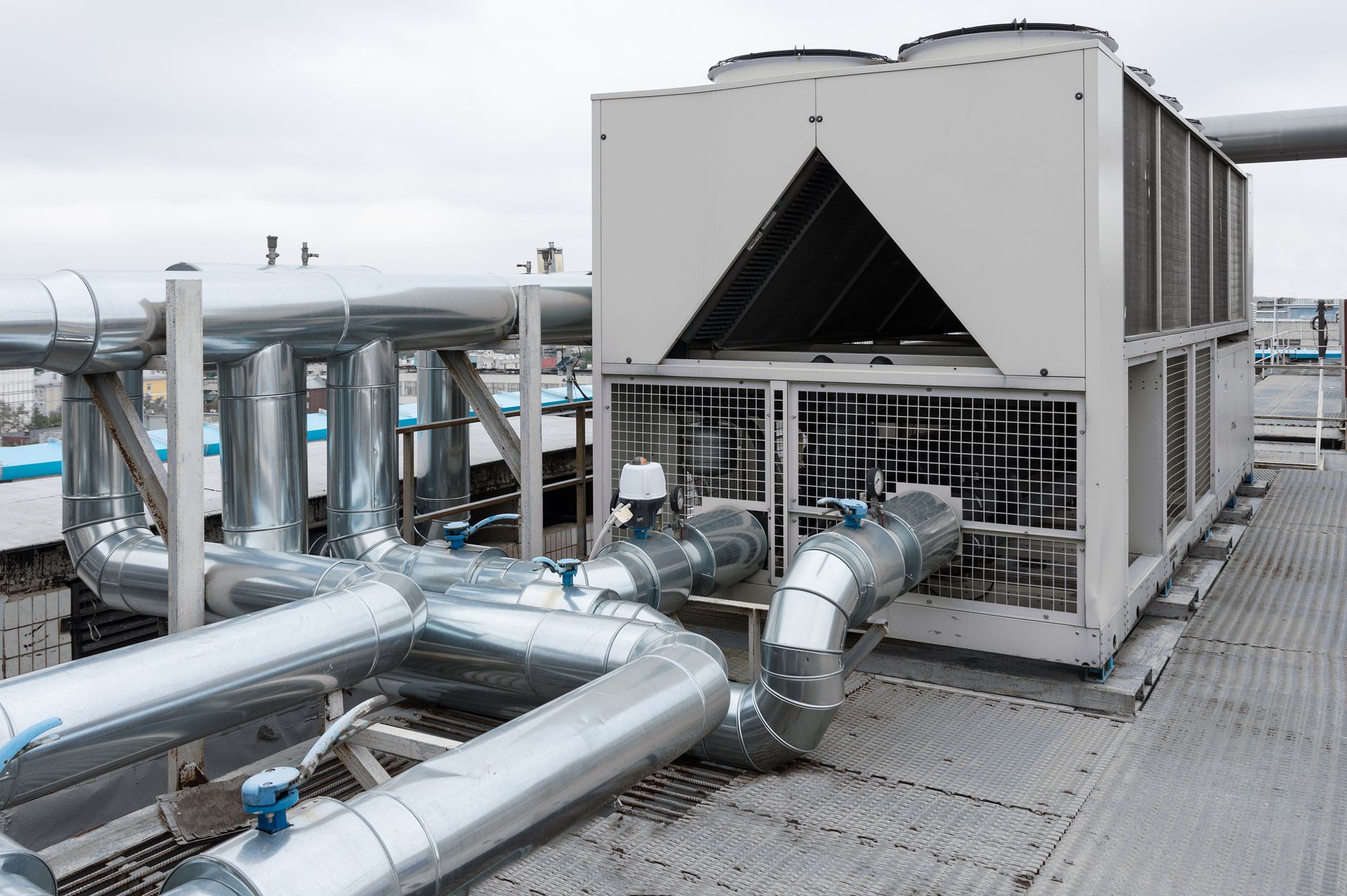 A large air conditioner on top of a building with pipes coming out of it.