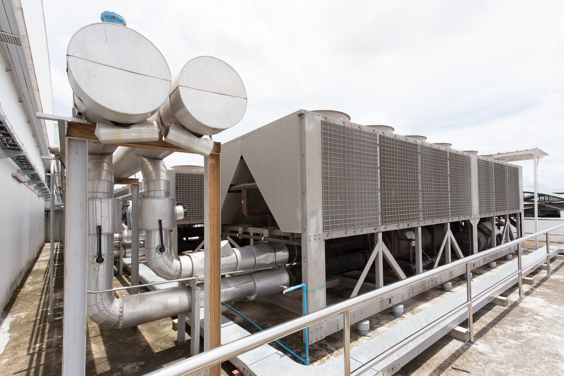 A large industrial chiller is sitting on top of a building.