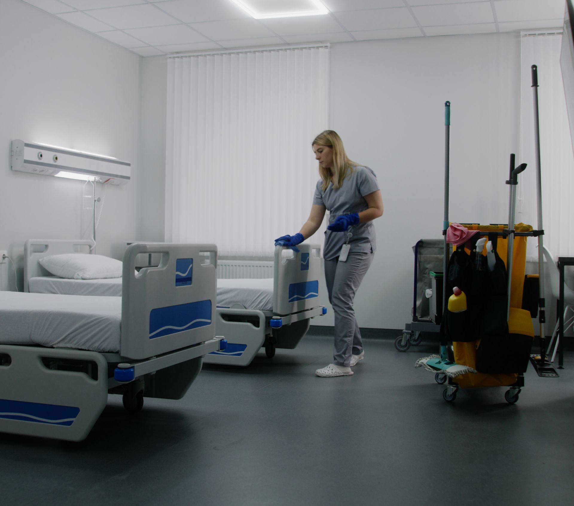 A woman is cleaning the floor of a hospital room.