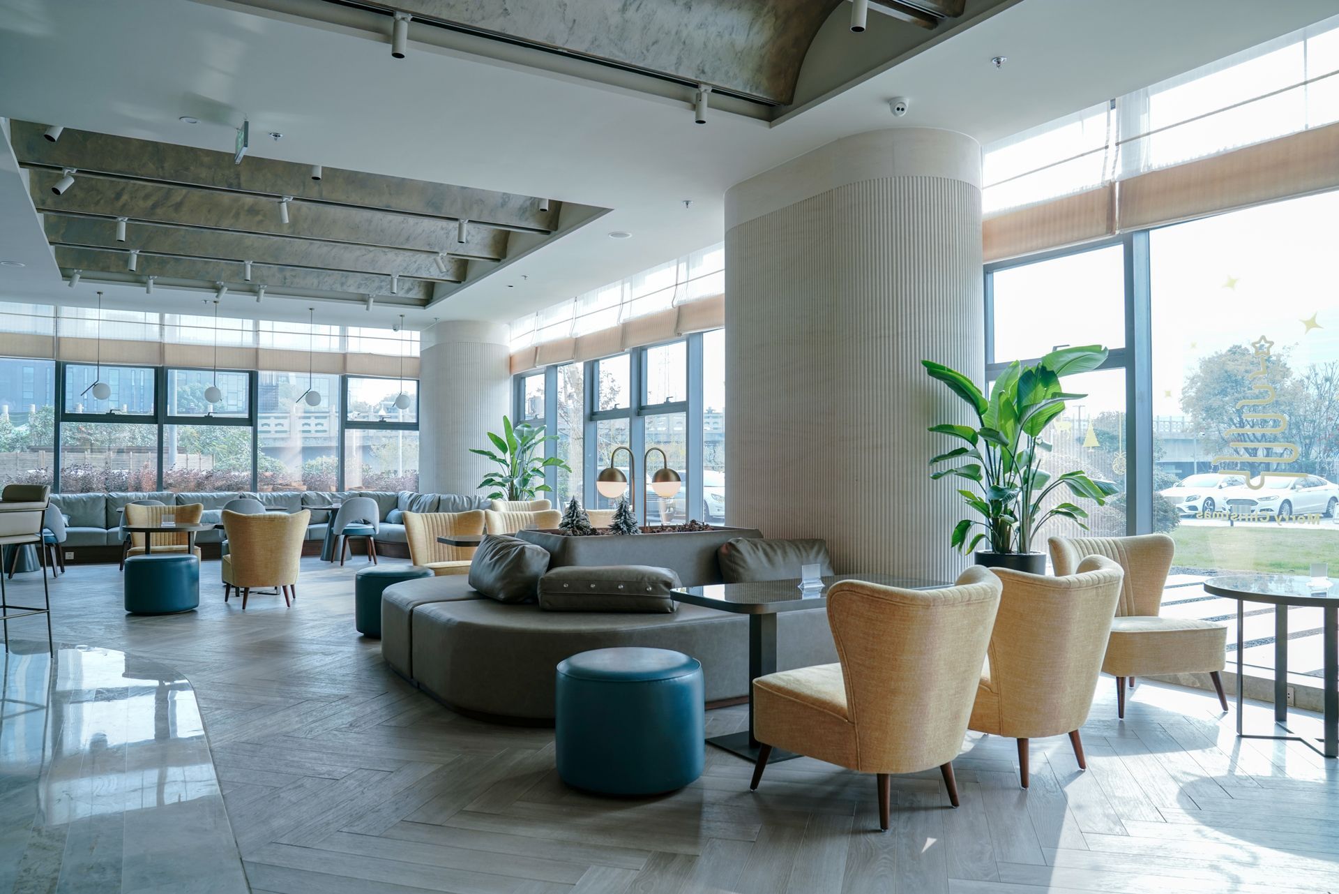 Bright modern lobby lounge with sofas, chairs, plants, and large windows overlooking water
