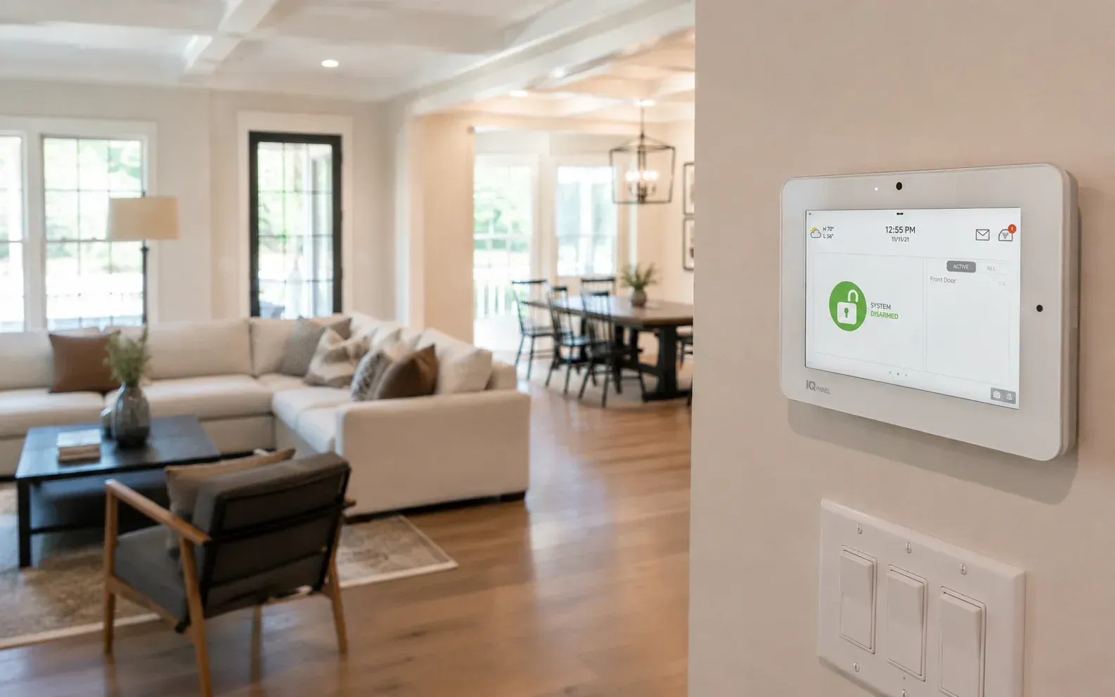 Wall-mounted touchscreen panel in a modern living room, displaying a smart home security system.