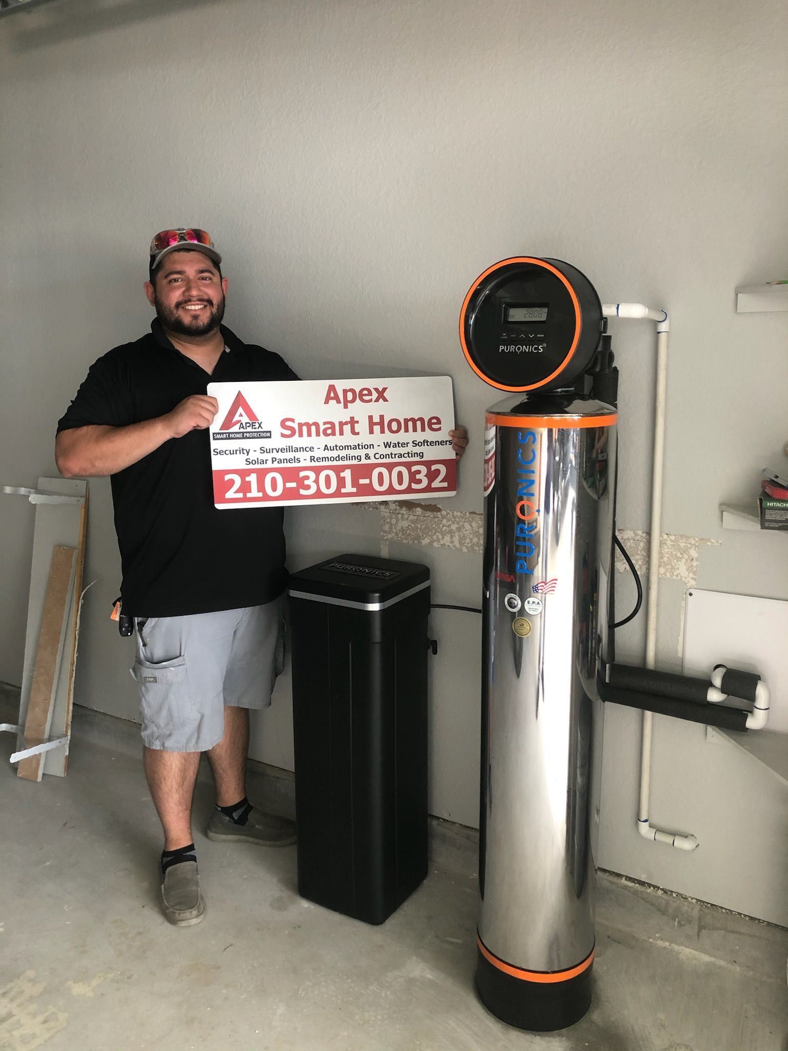 Man holding a Smart Home sign beside a shiny cylindrical appliance in a garage or utility room