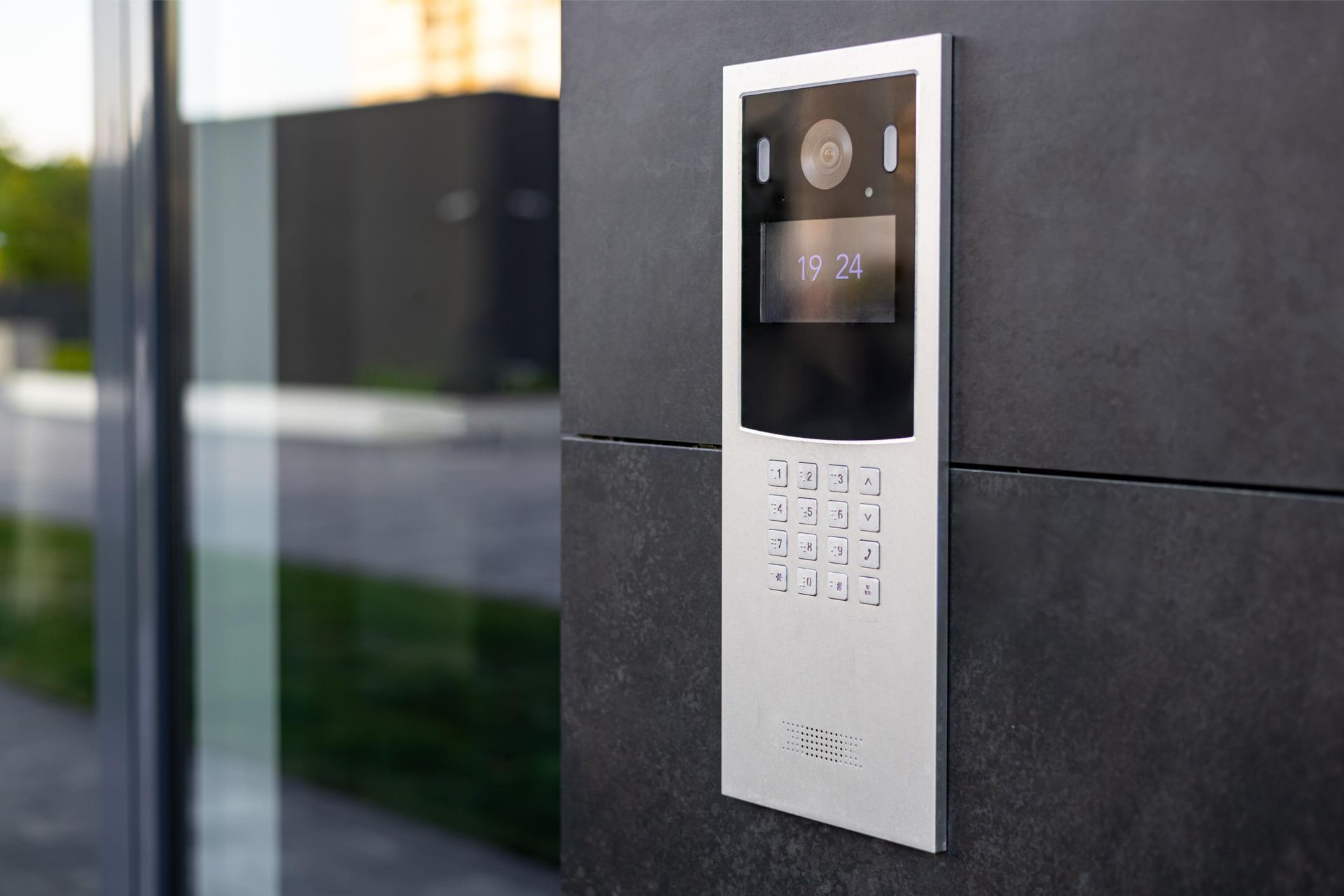 Wall-mounted intercom keypad and camera on a dark exterior building wall