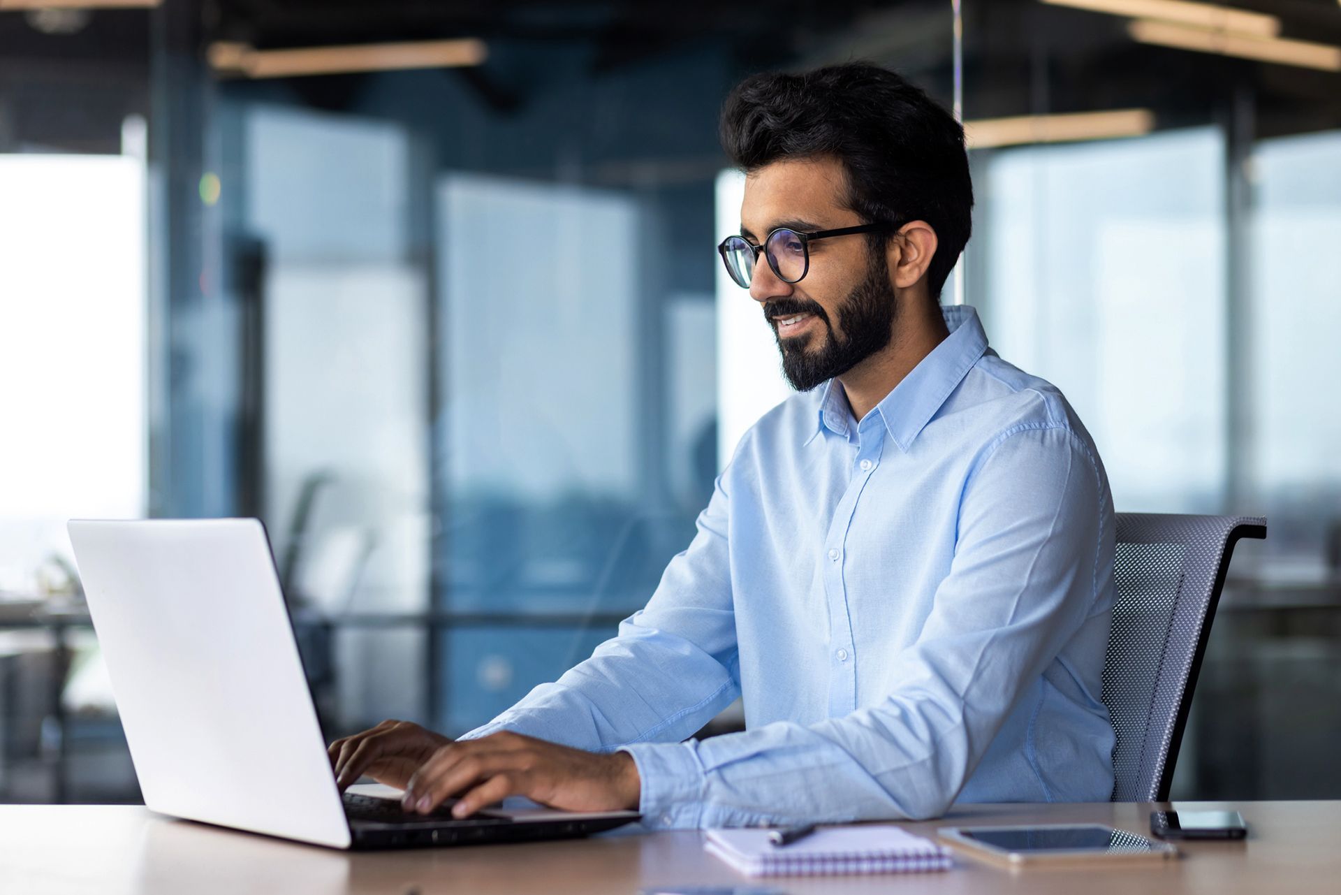 a man is sitting at a desk using a laptop computer .