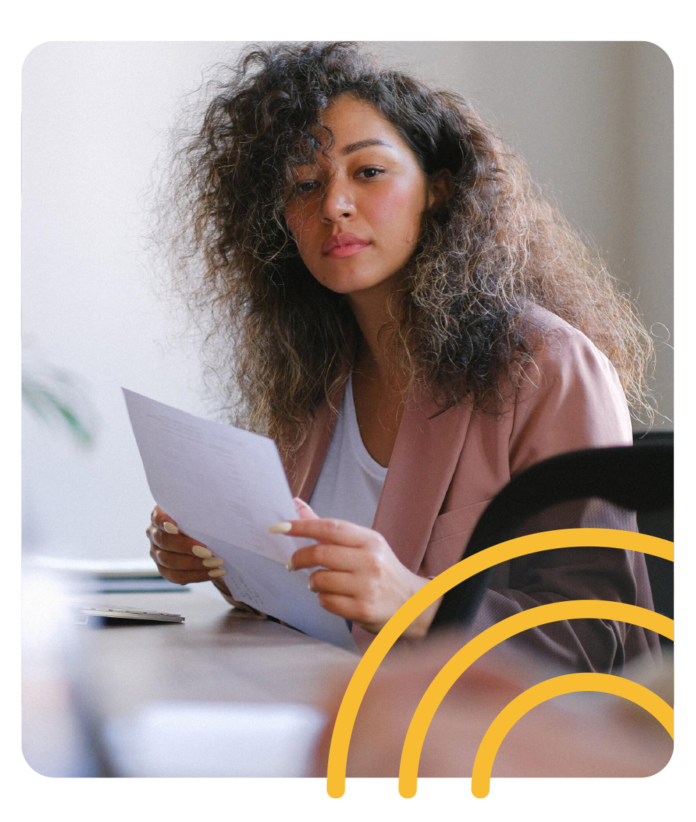 a woman is sitting at a table reading a piece of paper .